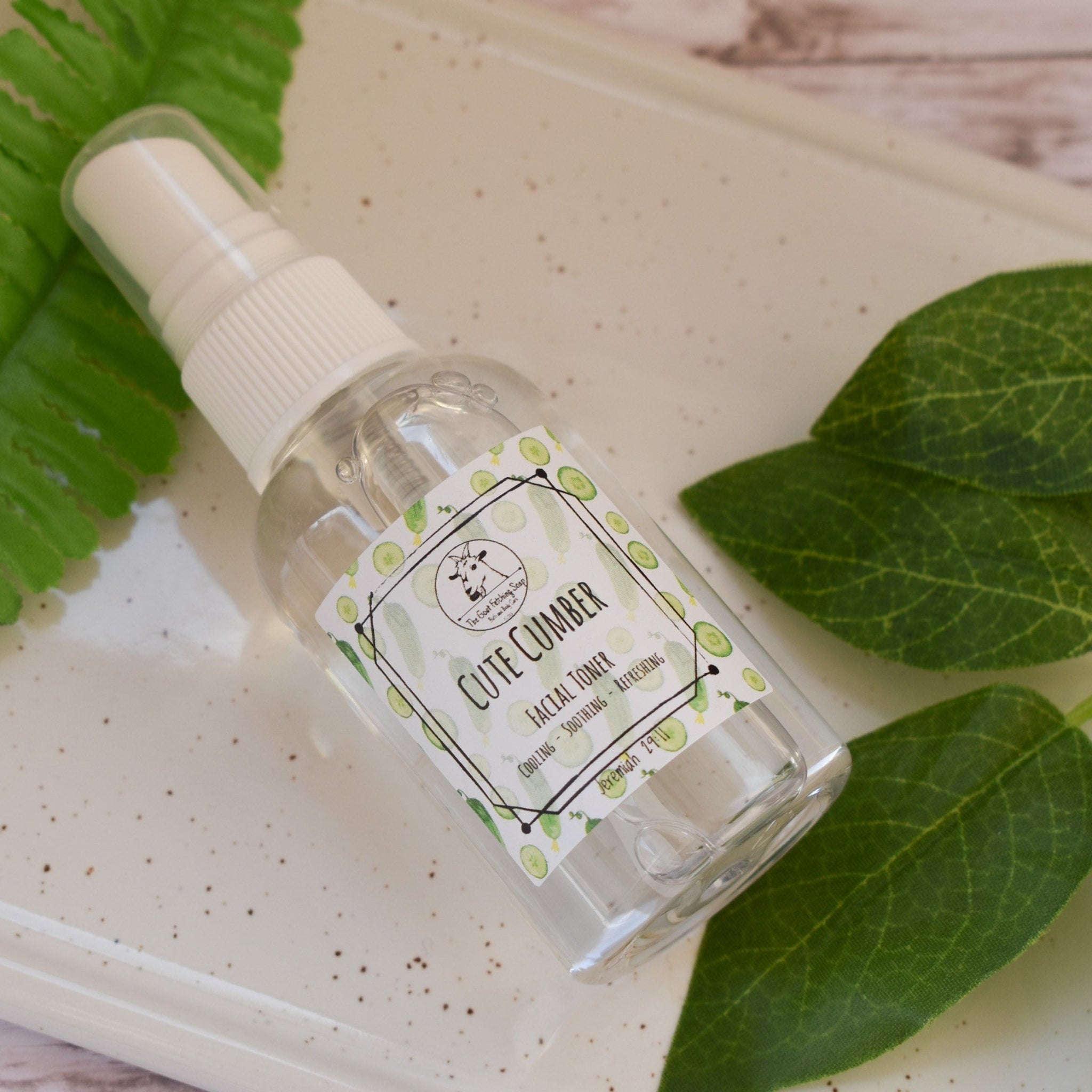 Facial toner spray bottle with clear liquid and white cap, Cute Cumber label visible on white surface