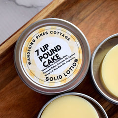 Solid lotion in metal tins with yellow label and light yellow balm on wood surface