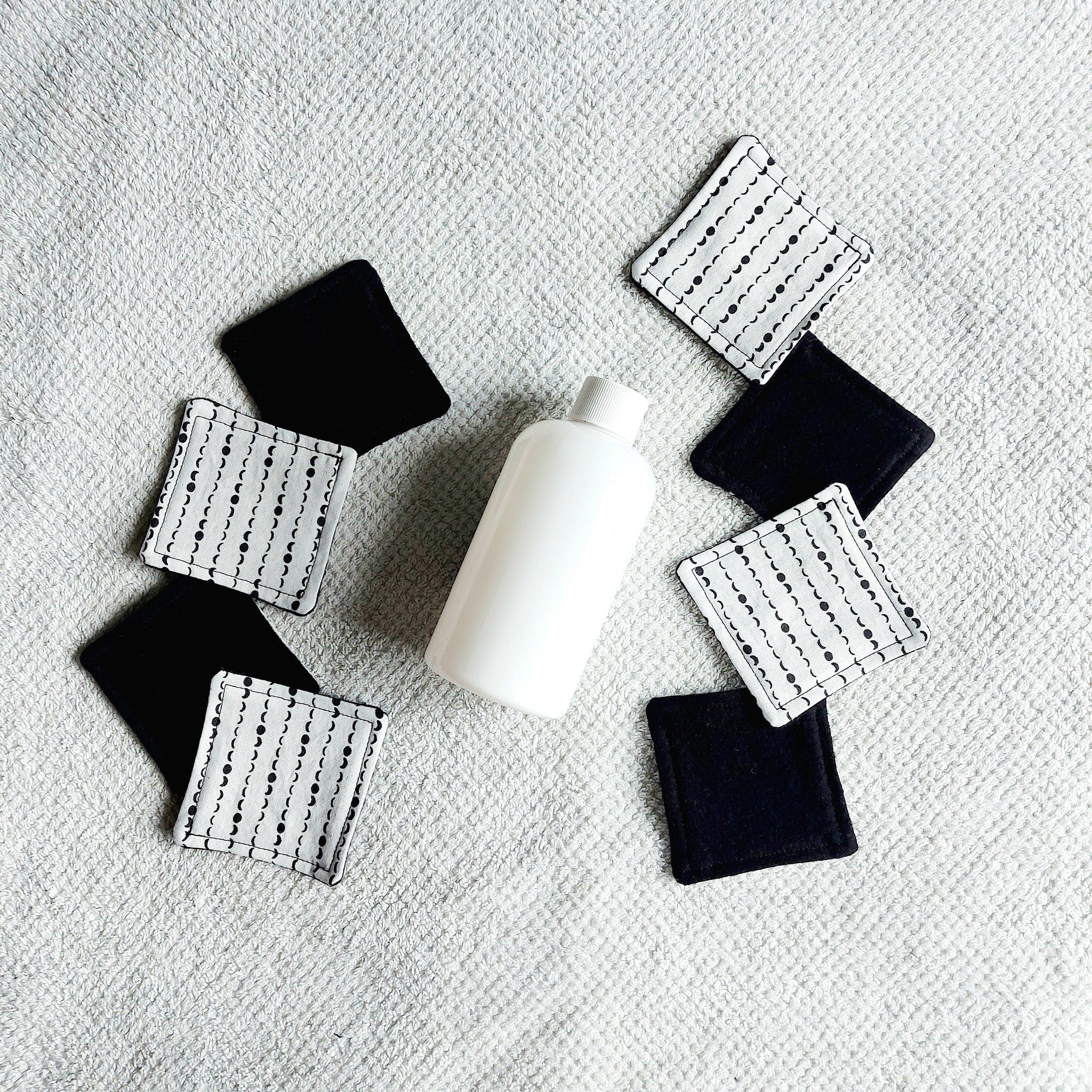 Makeup remover pads, black and white fabric with moon pattern, with white bottle on white towel