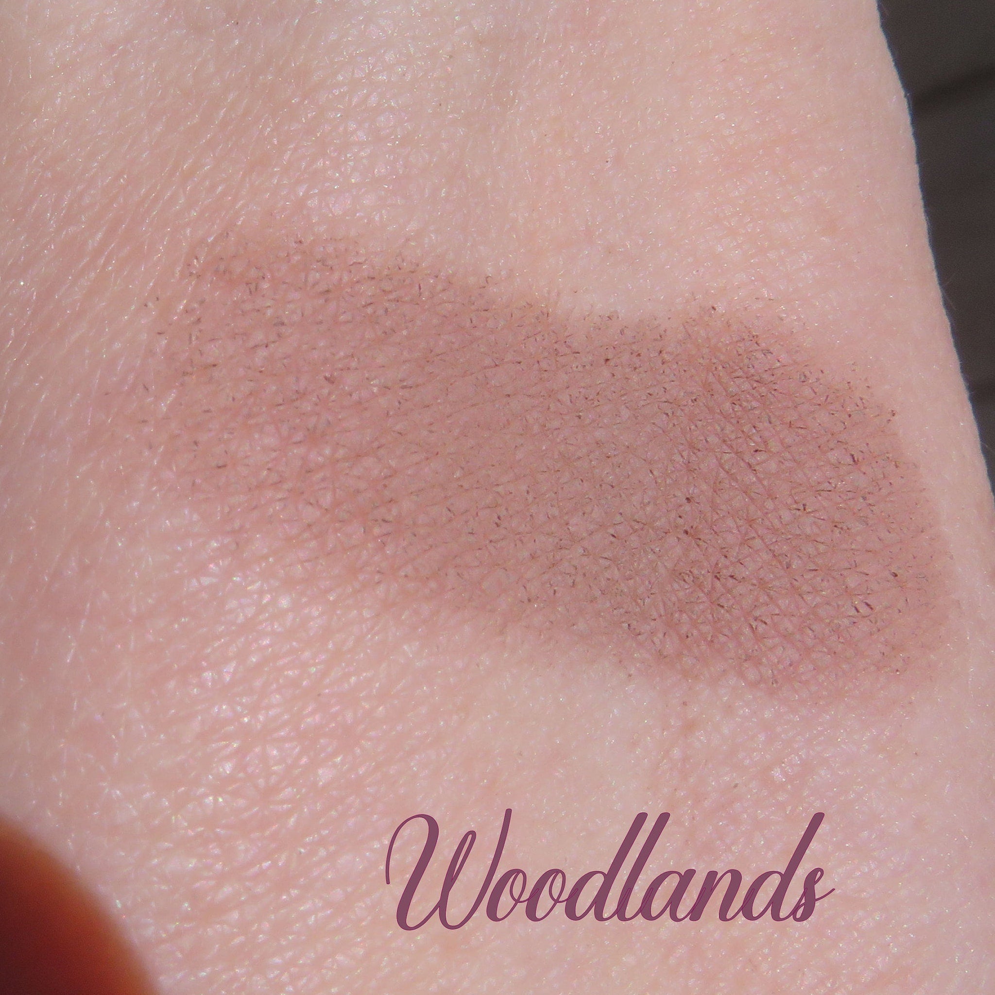 Side view of loose matte brown mineral eyeshadow in eco-friendly packaging with mica shimmer particles visible