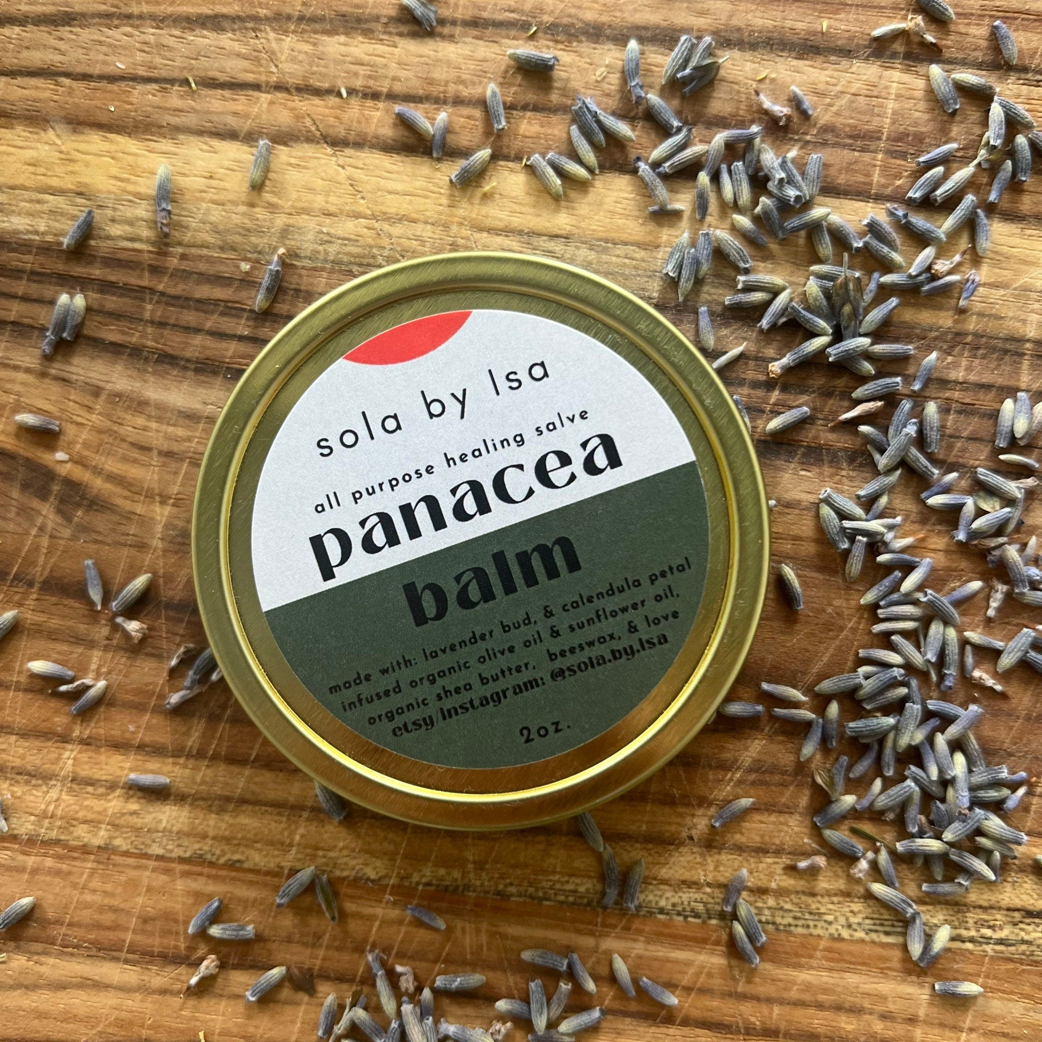 Balm tin with gold rim, green and white label, and lavender buds on wood surface sola by Isa balm
