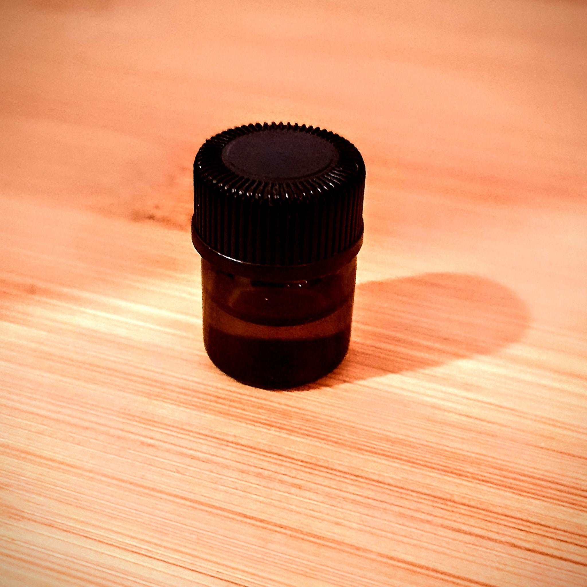 Small brown glass bottle with black cap on wooden surface