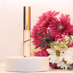 Lip gloss tube with gold cap and clear tube, A.Monét branding visible, on white stand