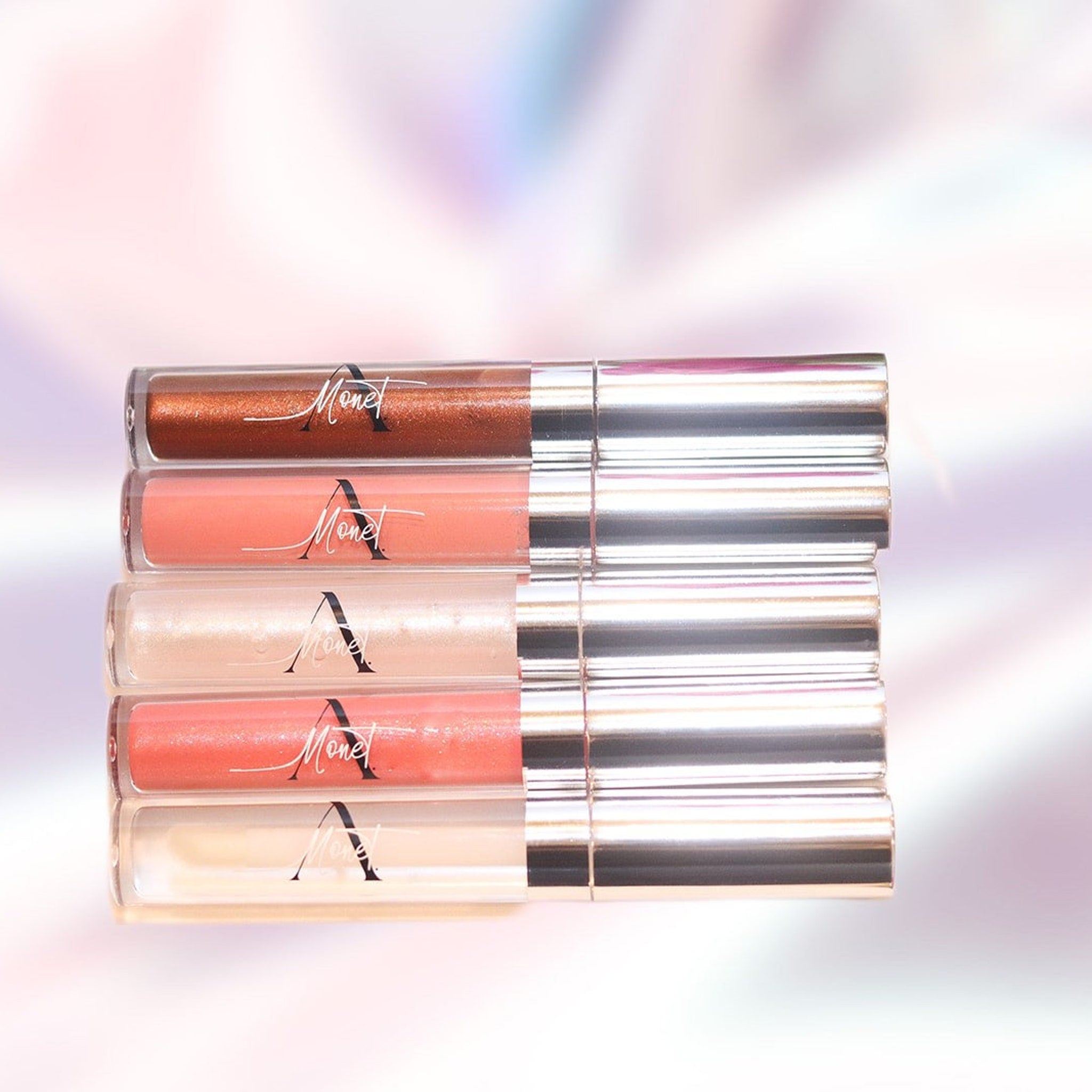 Lip gloss tubes with clear, silver, and colored tubes, Monet brand name visible