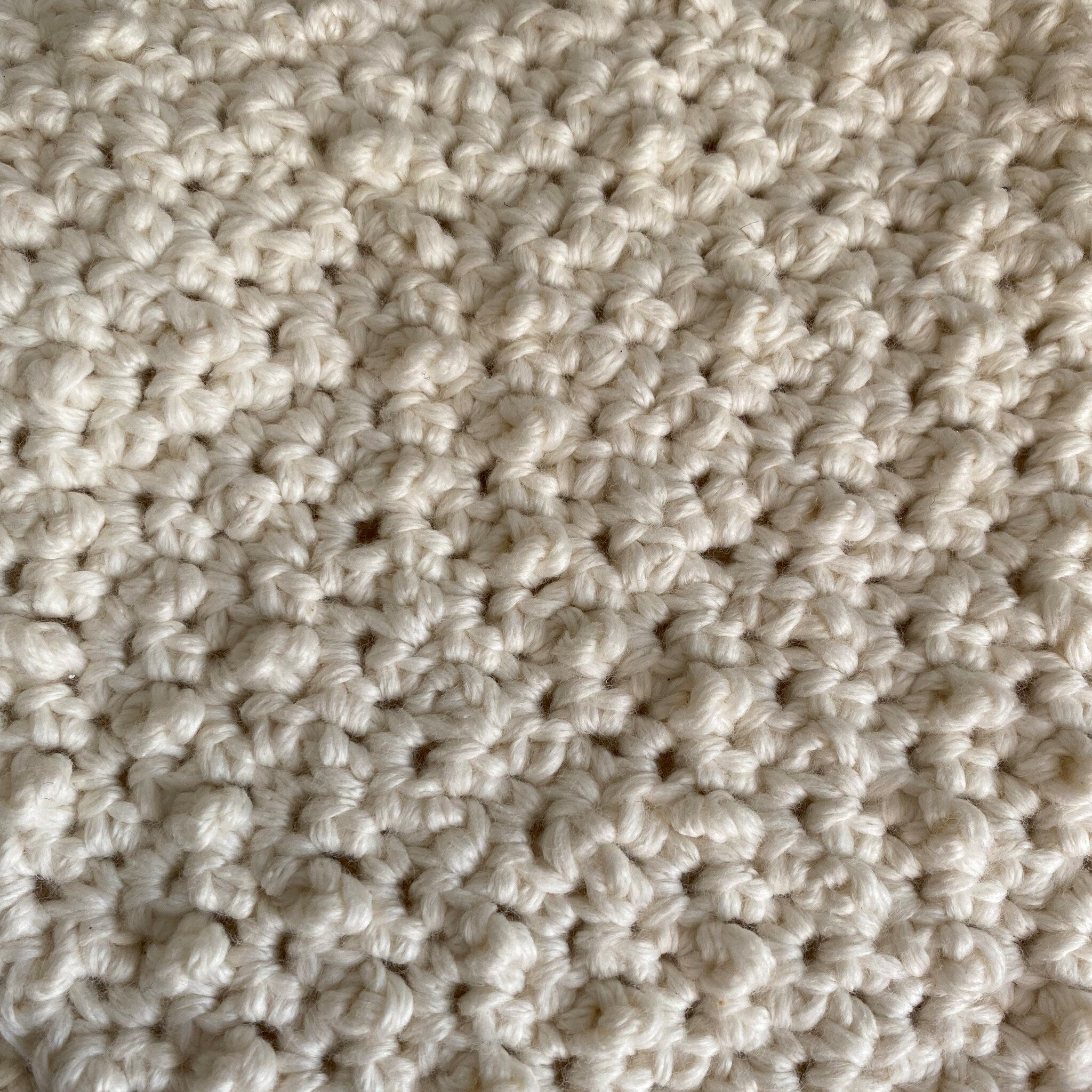Crochet texture off-white yarn with visible loops and knots, close-up view