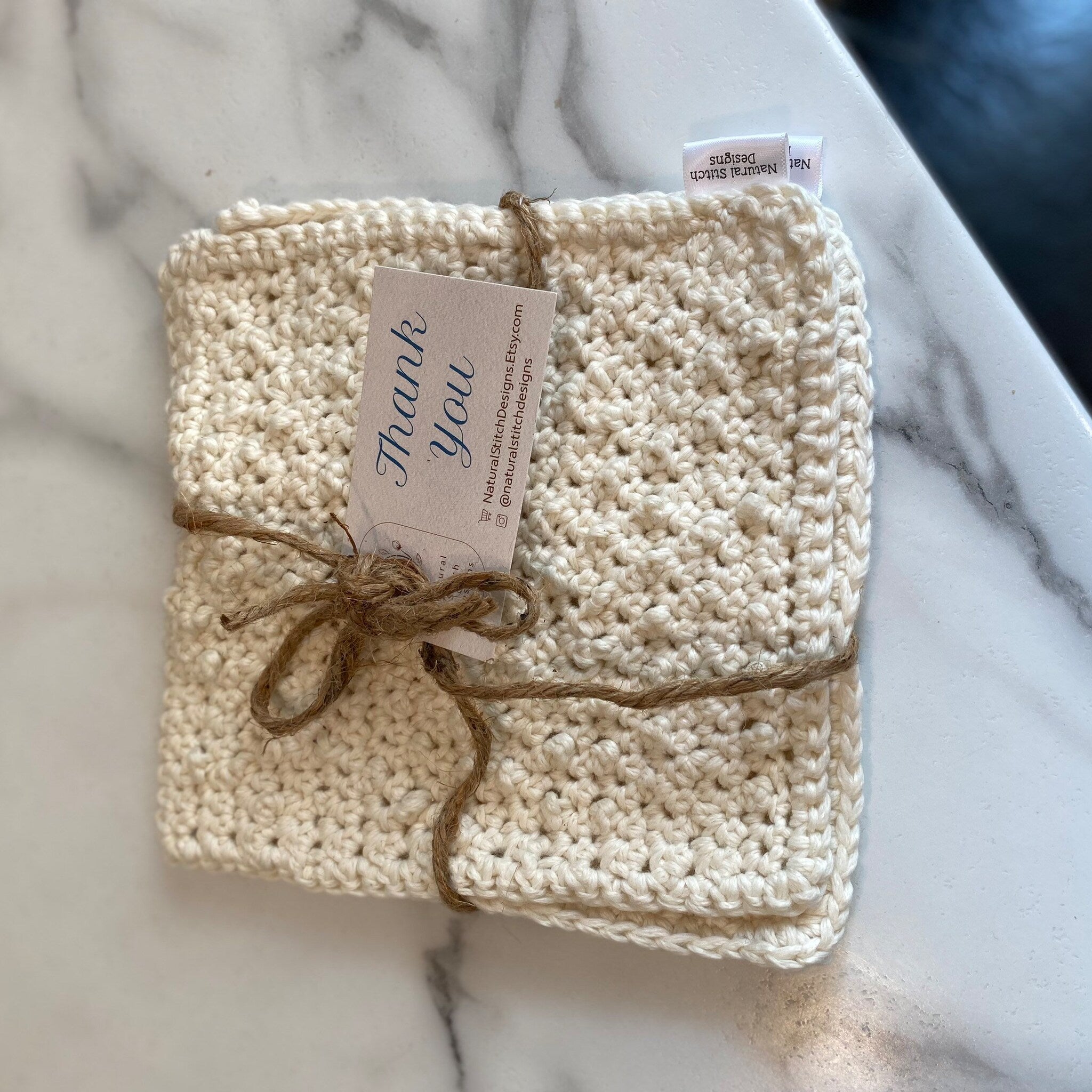 Crochet washcloths, cream-colored cotton, tied with twine, Natural Stitch Designs tag visible