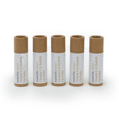 Lip balm tubes with brown and white labels, natural cardboard tops, and "rooted by nature" text.