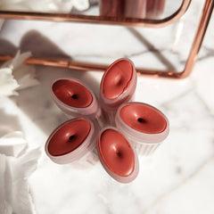 Lip balm sticks with coral color, oval shape, and clear plastic casing on marble surface