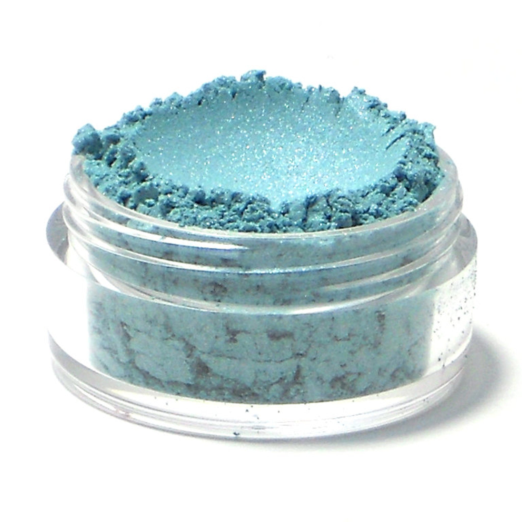 Frosty aqua blue mineral eyeshadow in compact case with shimmer finish, shown open on marble surface.