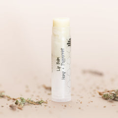 Lip balm tube, white with text, light yellow balm visible, HandCraft Skincare product