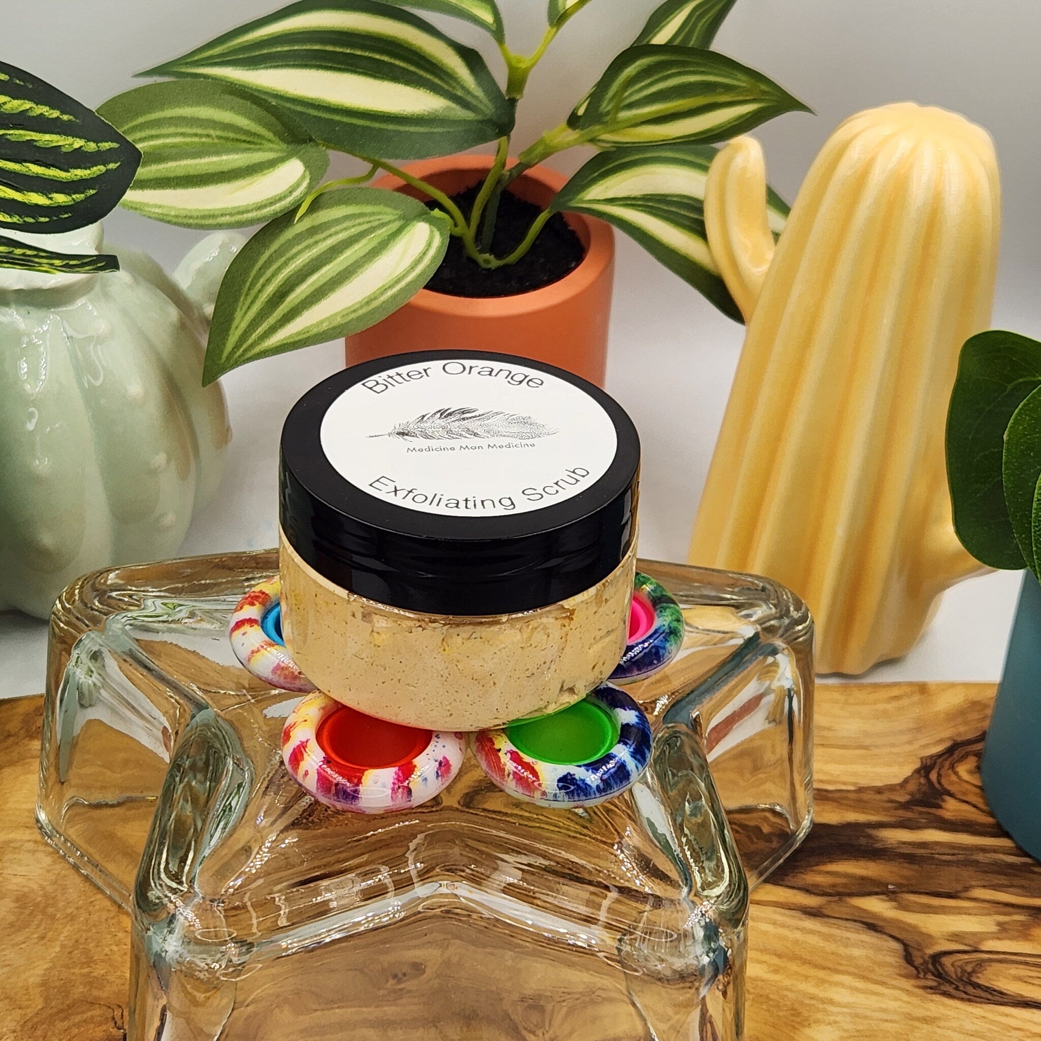 Exfoliating scrub jar with black lid, tan contents, and "Bitter Orange" label on white background