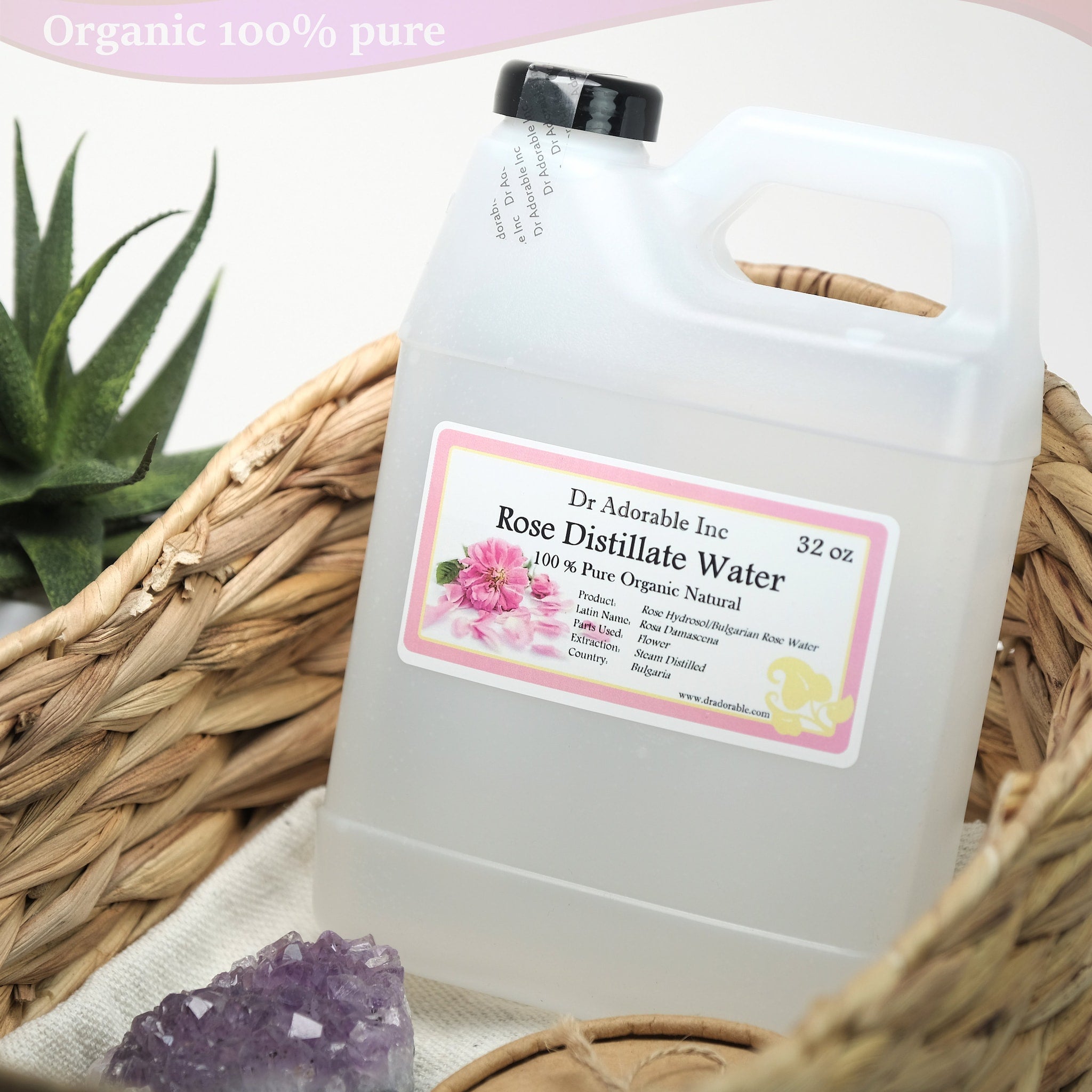 Rose distillate water in clear plastic jug with black cap, Dr Adorable Inc label, and woven basket