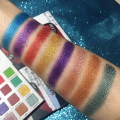 Close-up of hand applying shimmery pink eye shadow from anime-themed palette with small brush