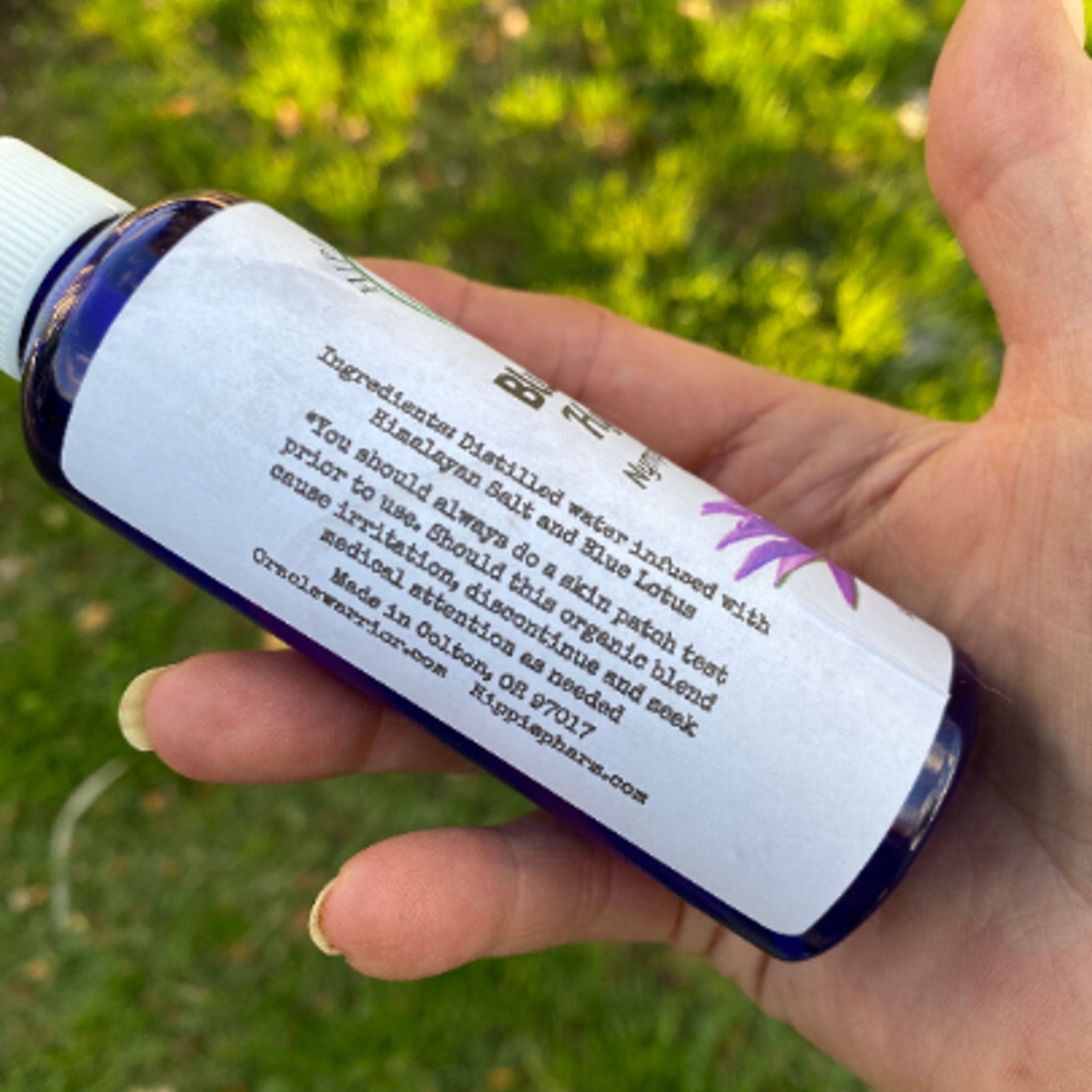 Blue glass bottle with white label held in hand, with text visible