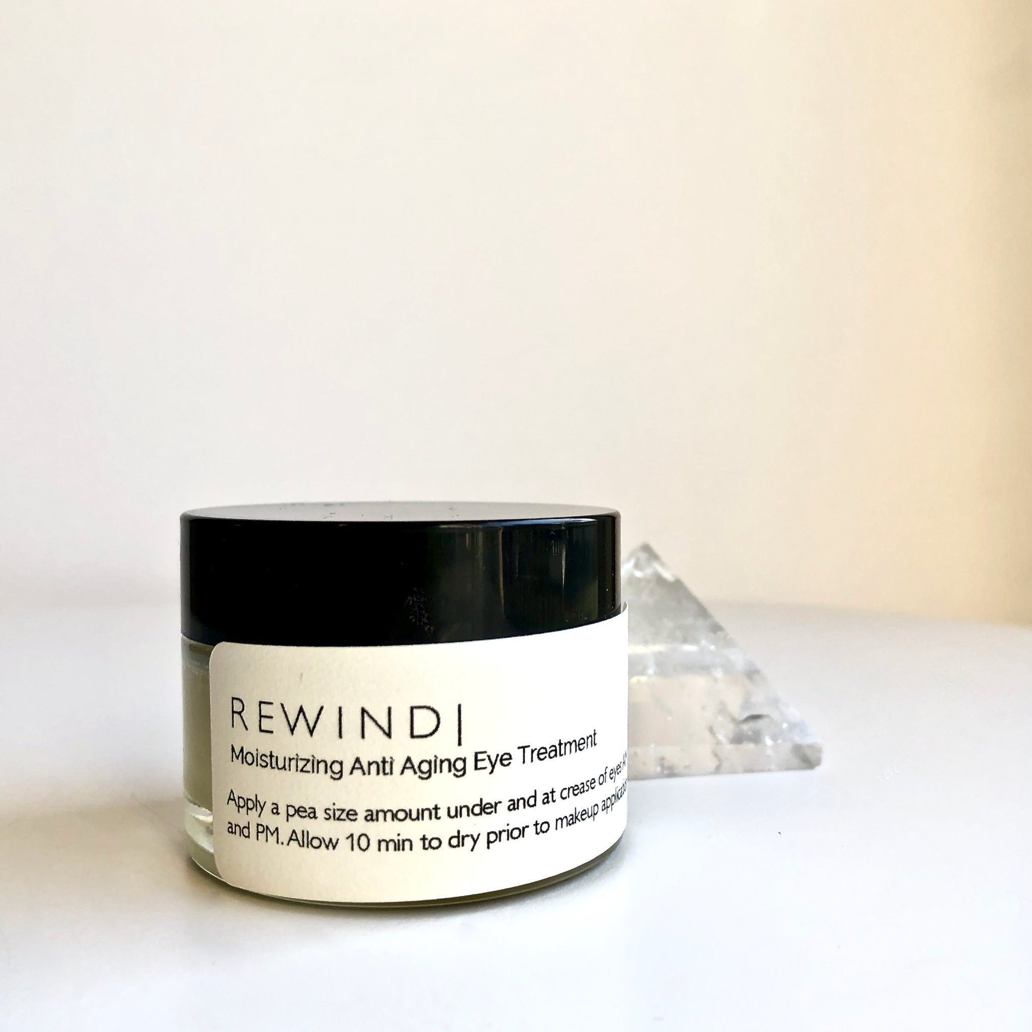 Eye treatment jar with black lid and white label, REWINDI brand name visible on label