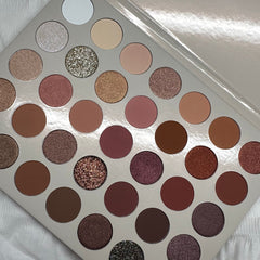 Close-up of 35 vibrant eyeshadow pans in matte, shimmer, and metallic finishes arranged in sleek black palette