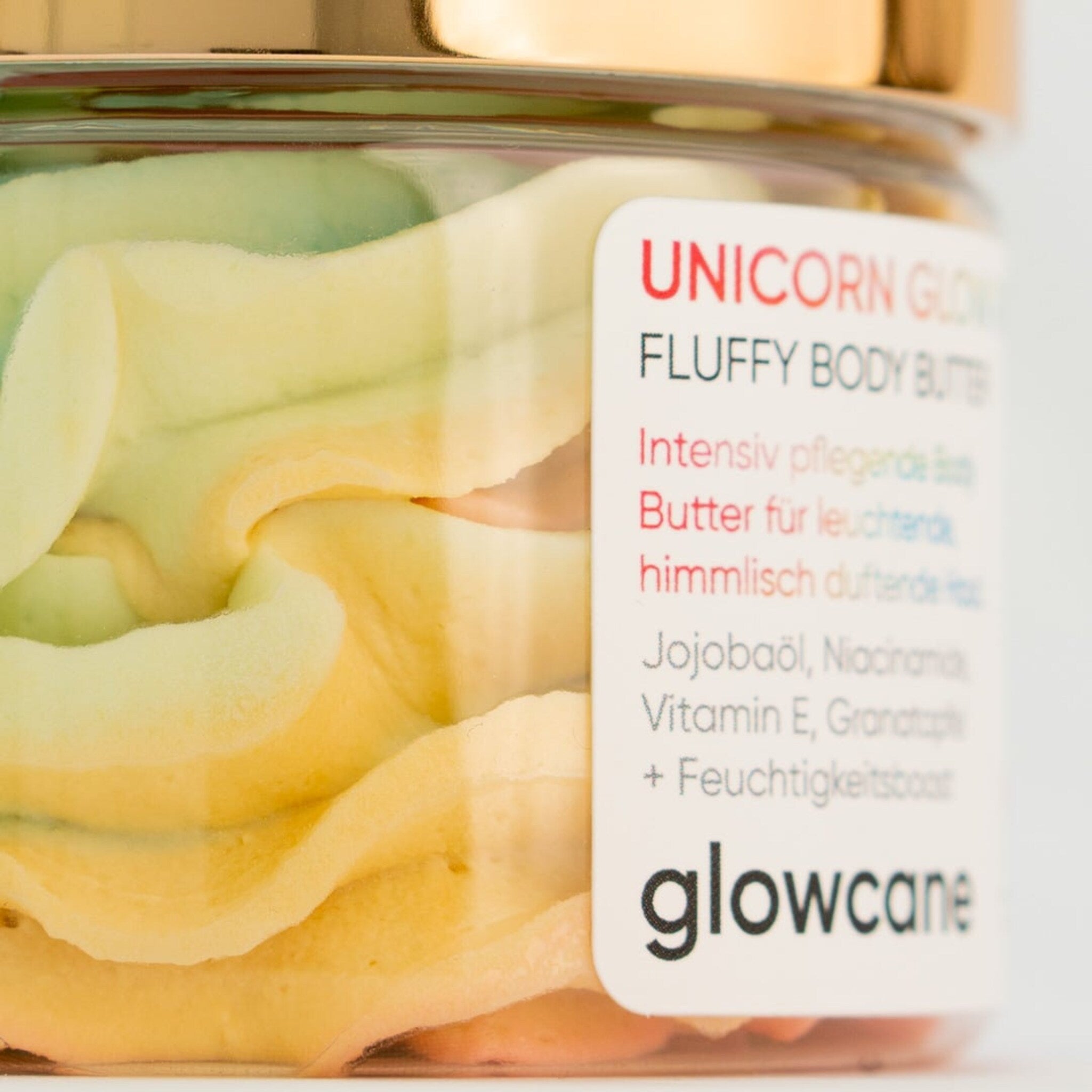 Hand applying unicorn glow body butter from a white jar onto smooth skin, showing rich texture