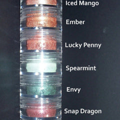 Side view of green eyeshadow stack showing seven matte and shimmer shades in circular pans with gold trim