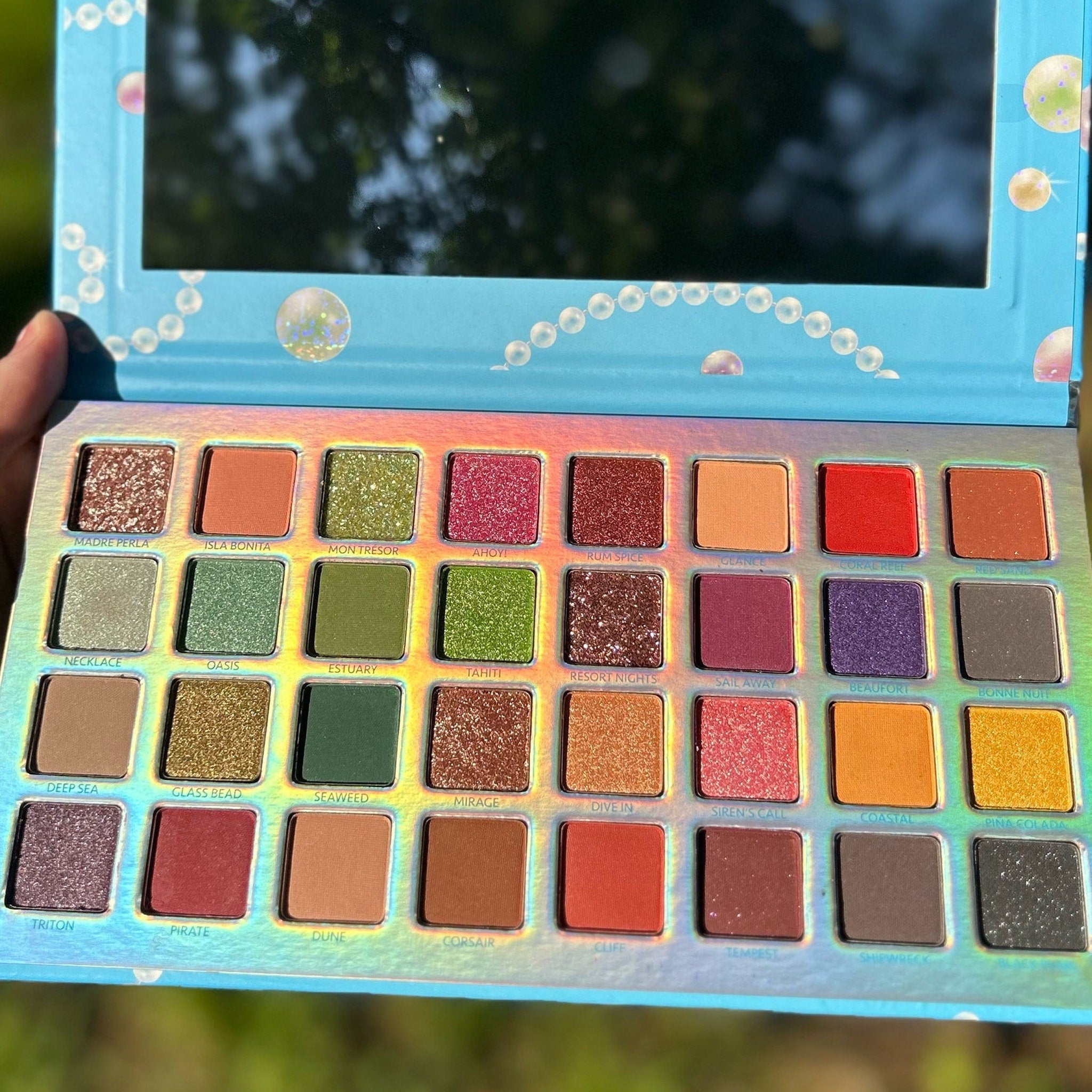 Close-up of fingertips applying shimmery peach eyeshadow from Pearl Paradise palette to eyelid crease
