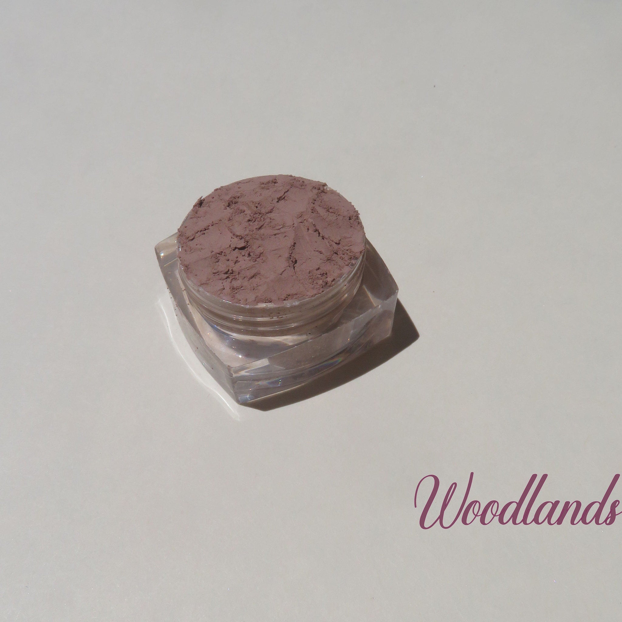 Side view of matte brown loose mineral eyeshadow in eco-friendly packaging with mica shimmer particles visible
