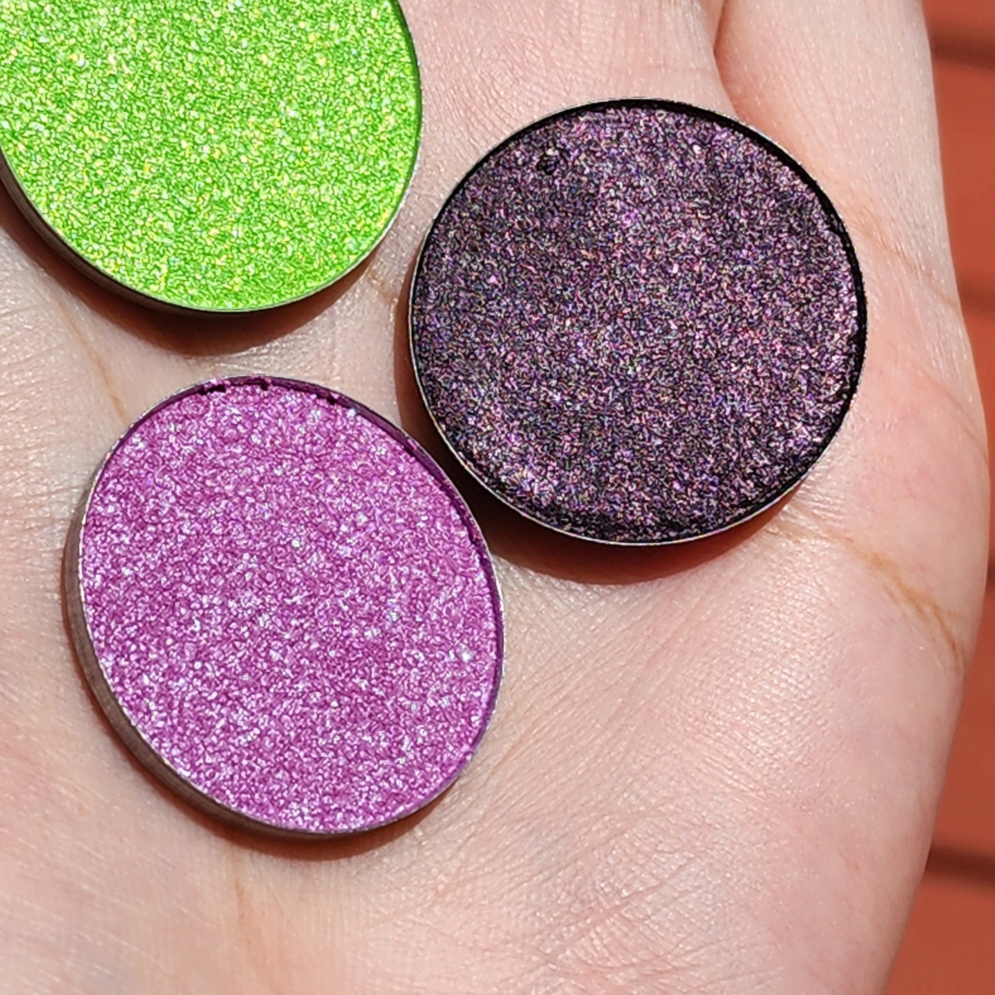 Vegan hybrid trichrome eyeshadow palette open, showcasing chameleon color shift shades with shimmer and glitter.
