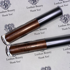Liquid eyeshadow tubes, metallic brown and silver, with Luxhan Beauty branding visible