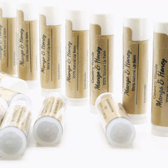 Lip balm tubes with brown paper label, white cap, and black text of "Mango & Honey" product name