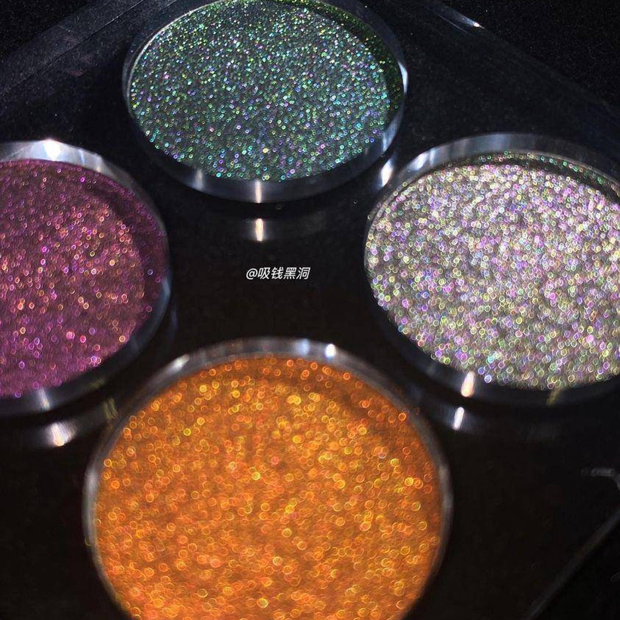 Eyeshadow pans with shimmering multi-color glitter, round metal containers, four shades visible