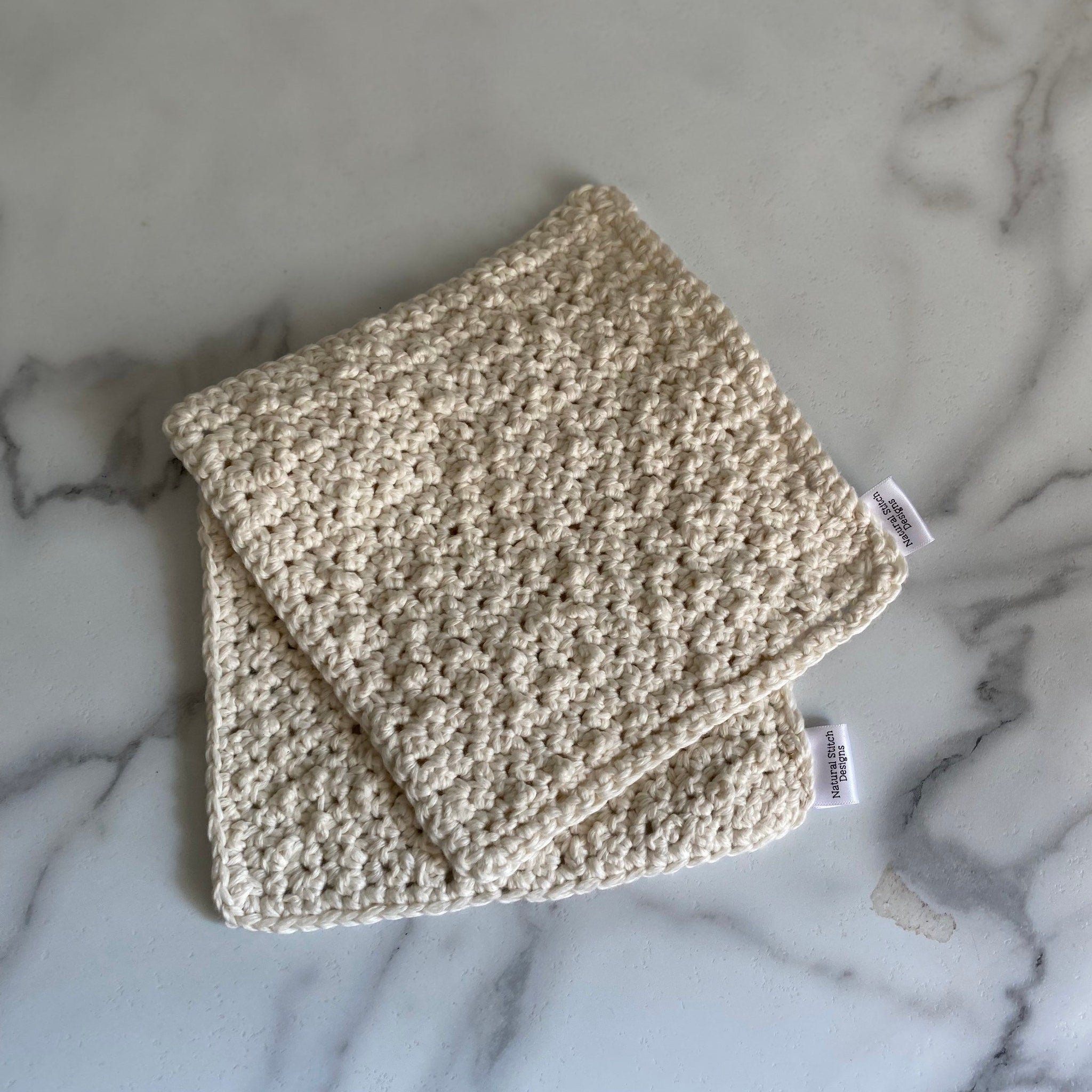 Crochet washcloths, cream-colored cotton, textured stitch pattern, with Natural Stitch Designs label visible