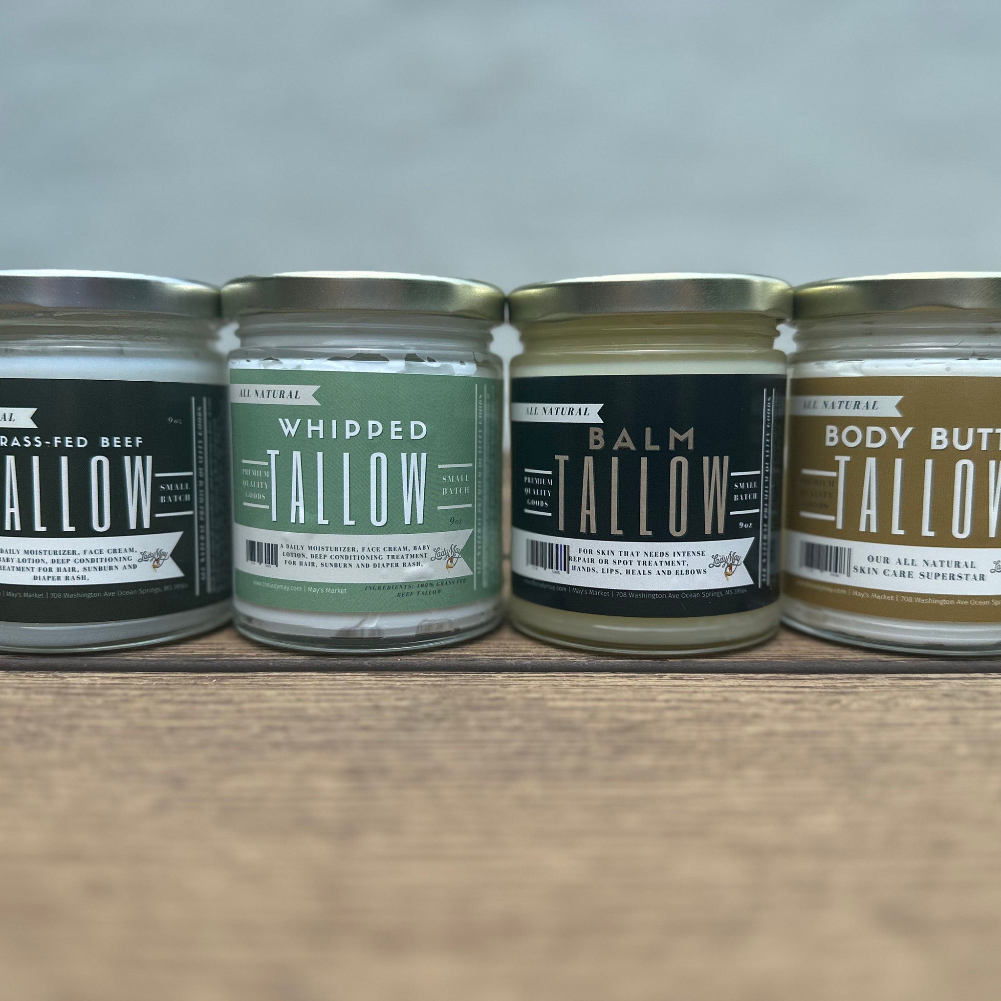 Tallow jars with gold lids, white and green labels, on wooden surface, Lady May brand visible