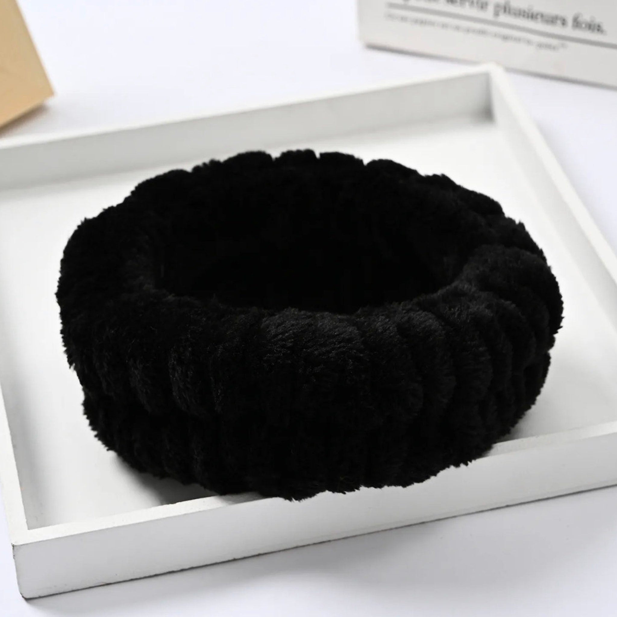 Black headband with ribbed texture and soft material on white tray