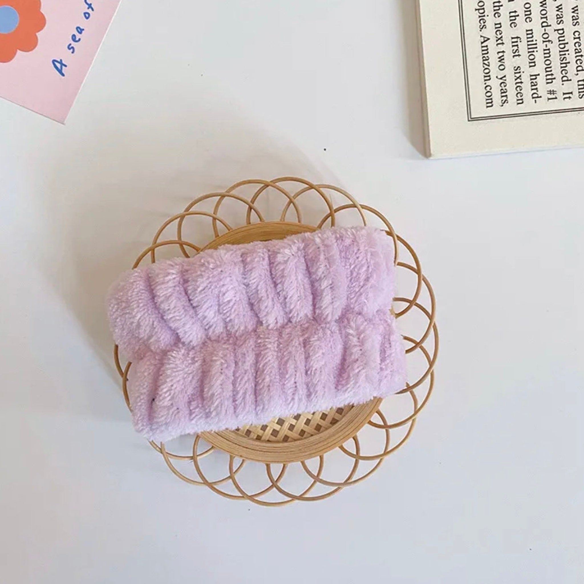 Headband, light purple fluffy material, on a woven circular tray