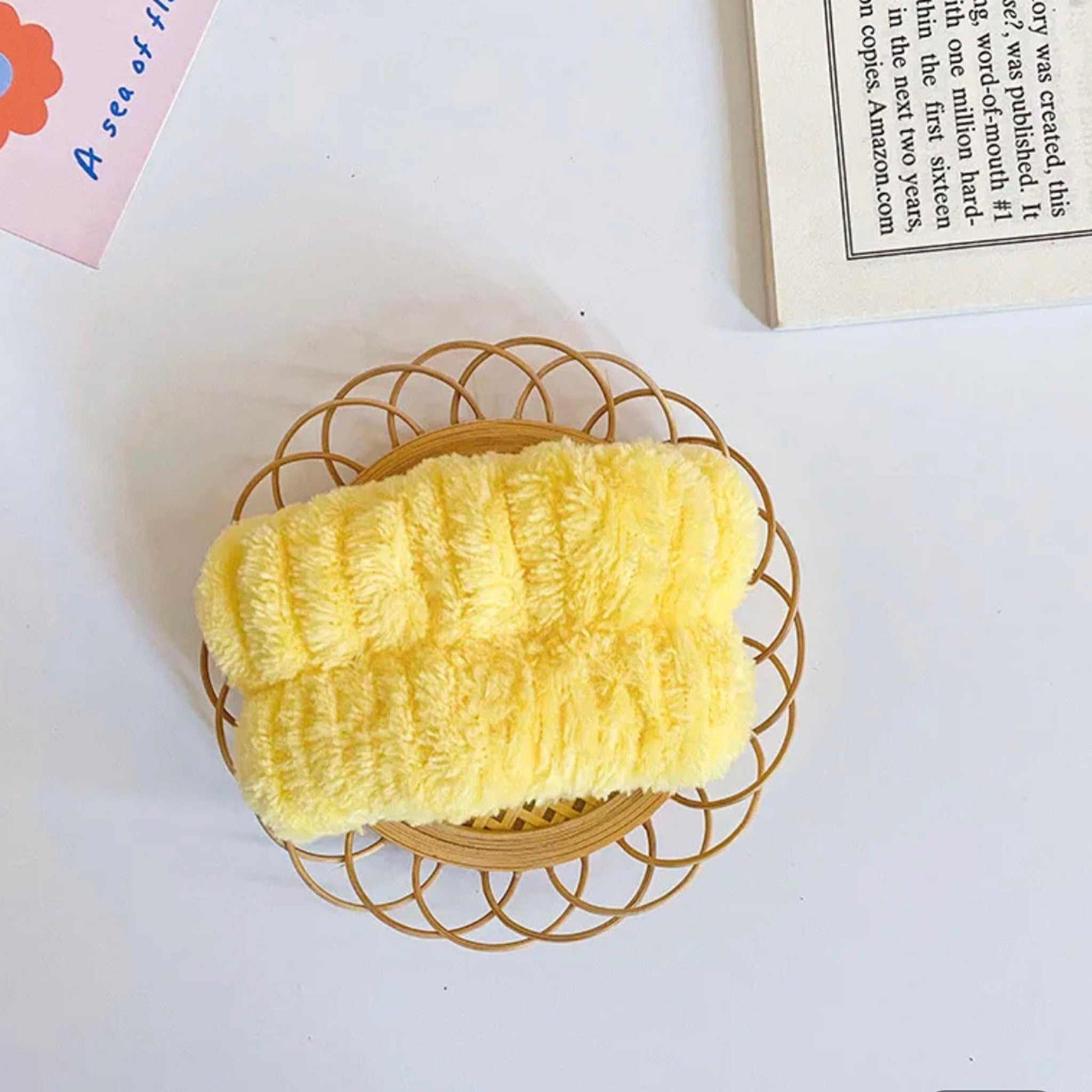 Yellow terry cloth headband on decorative wicker tray, top view