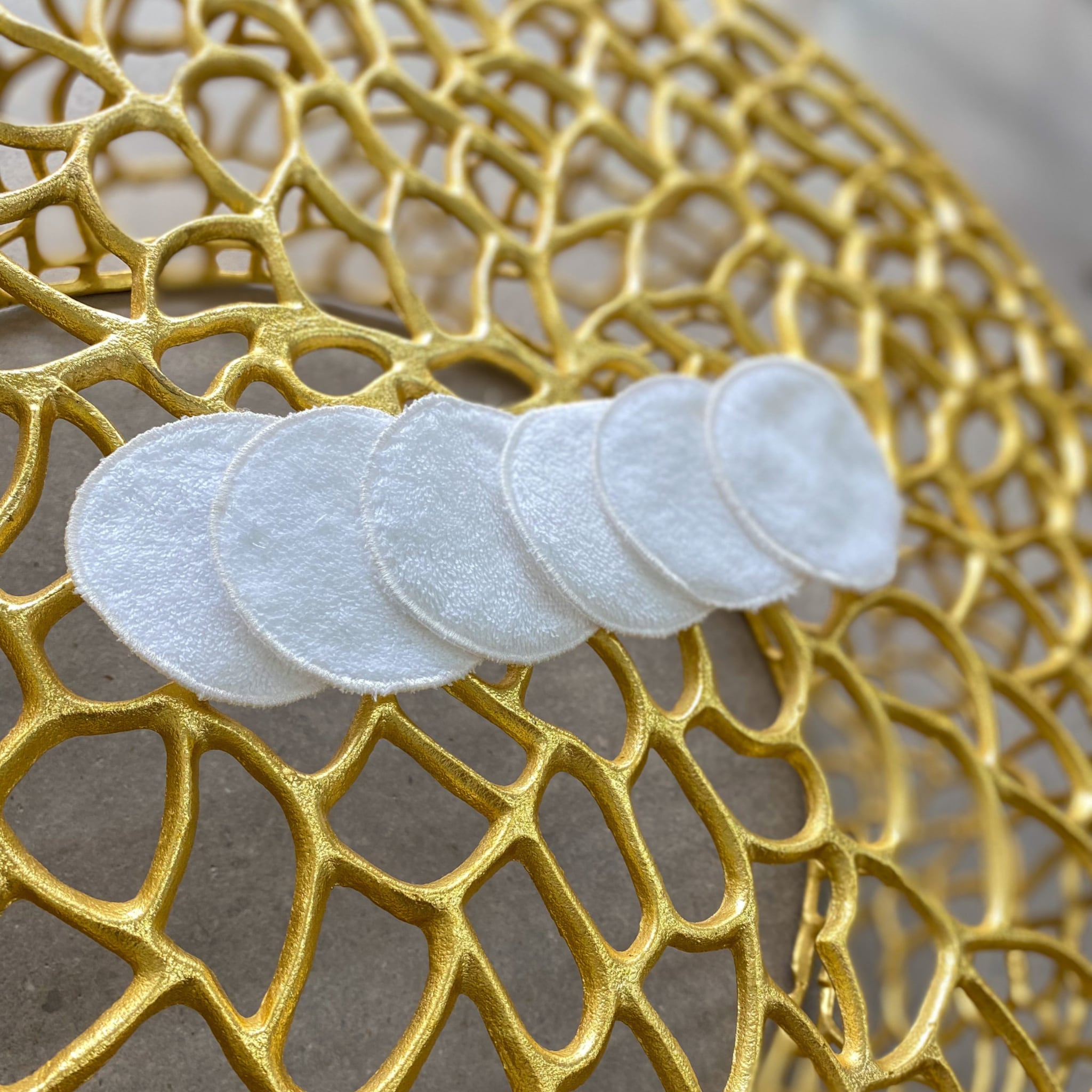 Reusable facial rounds, white cotton pads on gold patterned surface