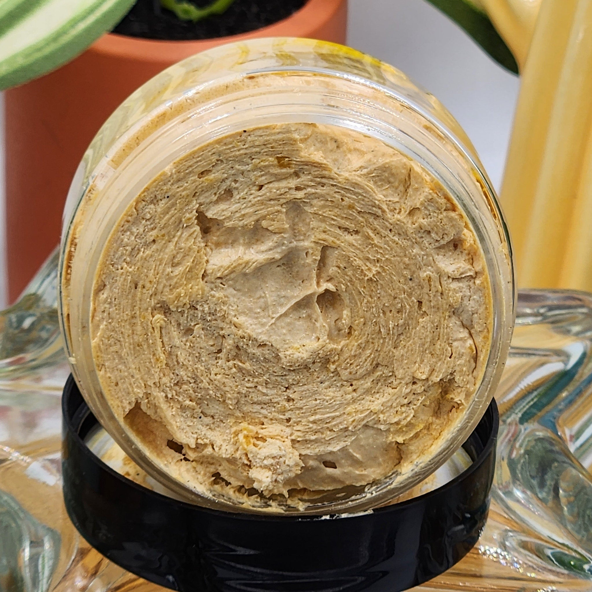 Creamy tan textured product in a clear glass jar with a black lid, close-up view