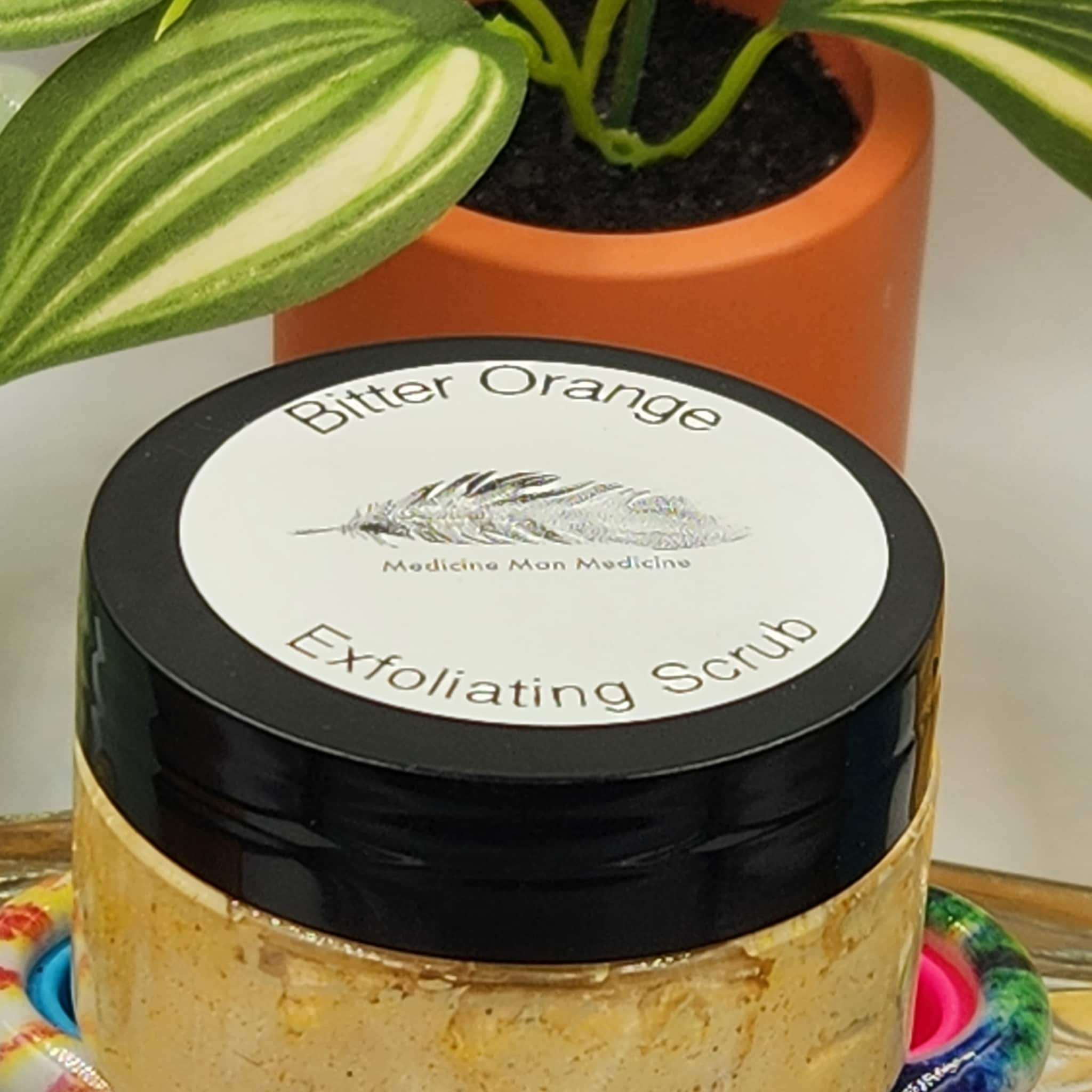 Exfoliating scrub jar with black lid, white label, and visible text "Bitter Orange" and "Exfoliating Scrub