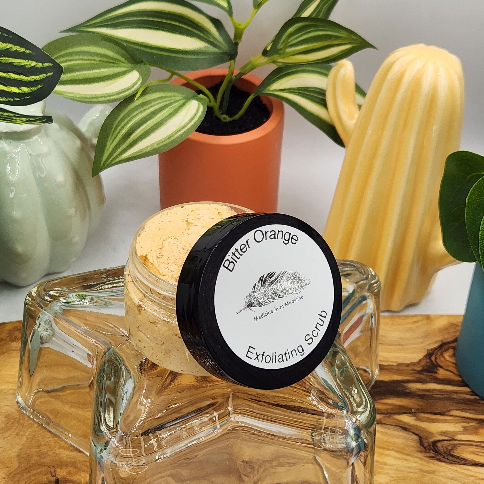 Exfoliating scrub jar with black lid, orange scrub, and "Bitter Orange" text on label