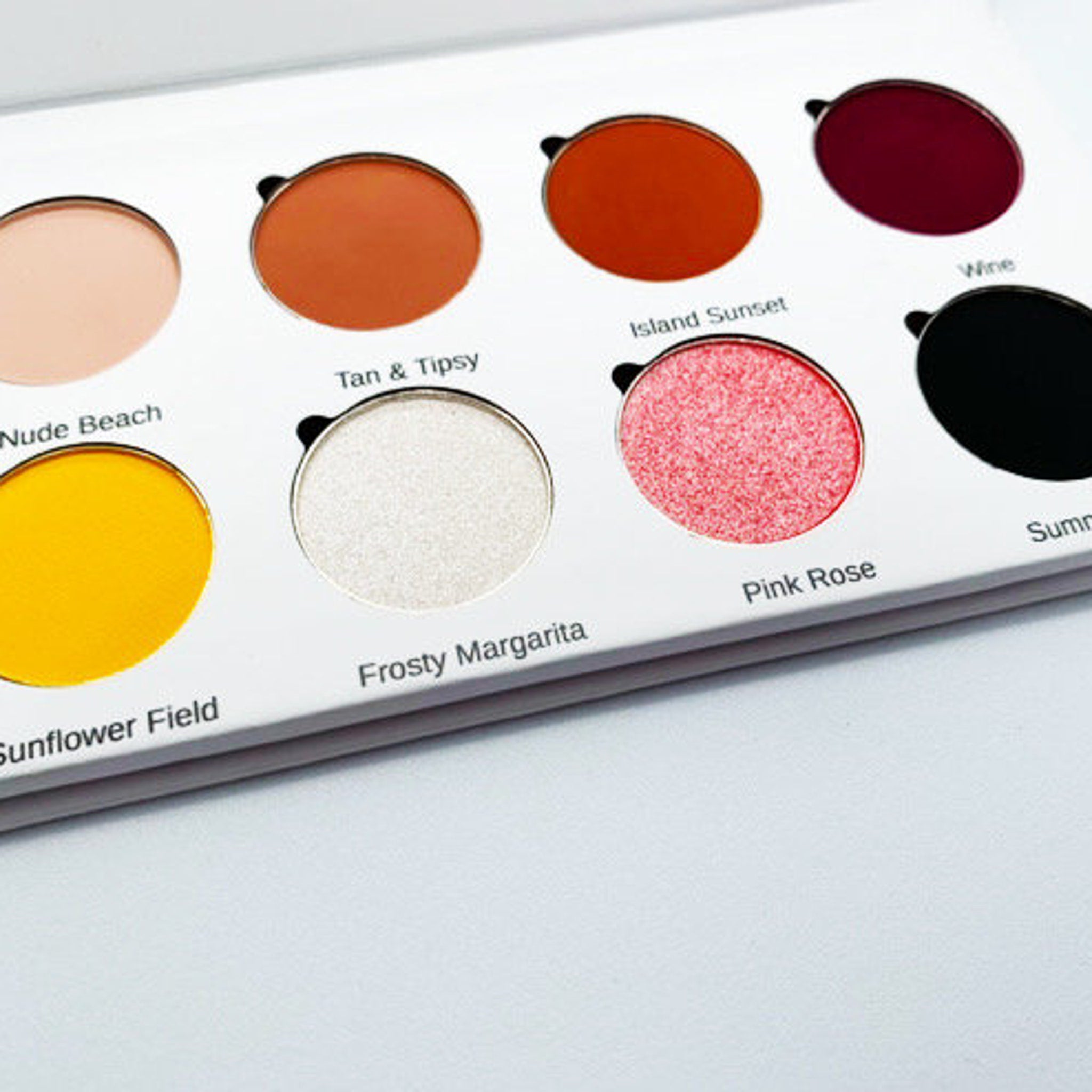 Hand applying golden shimmer eyeshadow from vegan palette with eco-friendly bamboo case