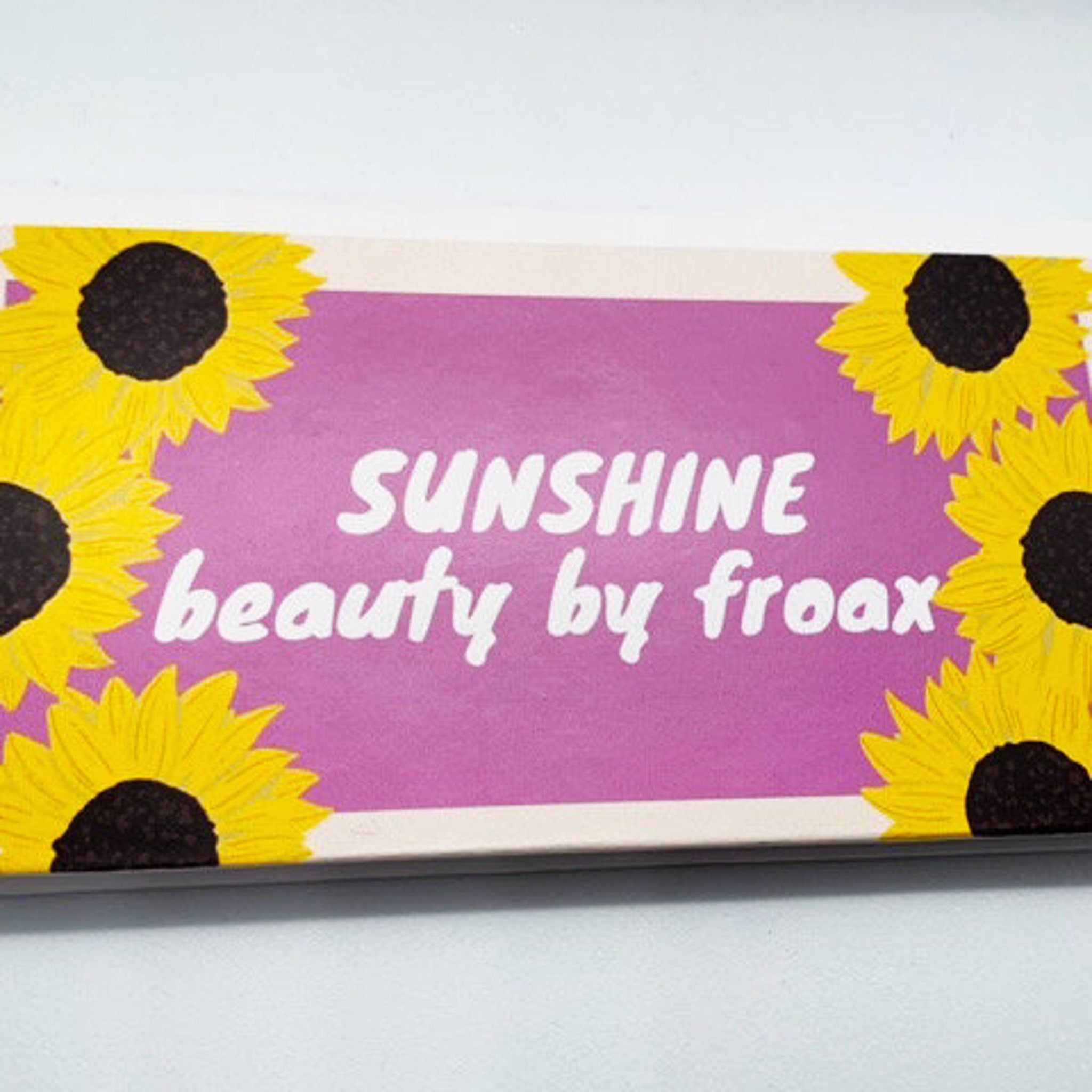 Side view of vegan eyeshadow palette showing sunset-inspired gradient colors in eco-friendly cardboard packaging