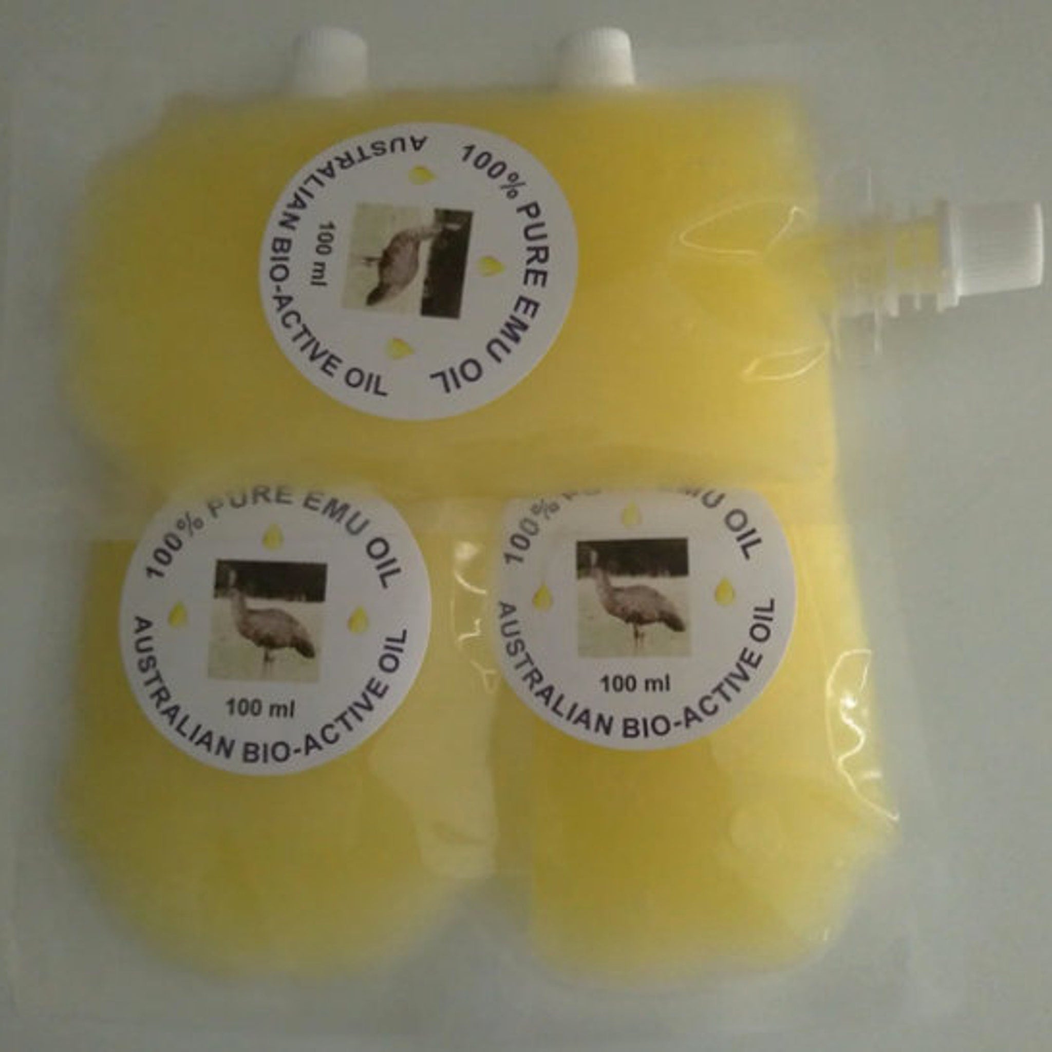 Close-up of golden amber emu oil in a sleek glass bottle with dropper, showcasing its smooth, luxurious texture.