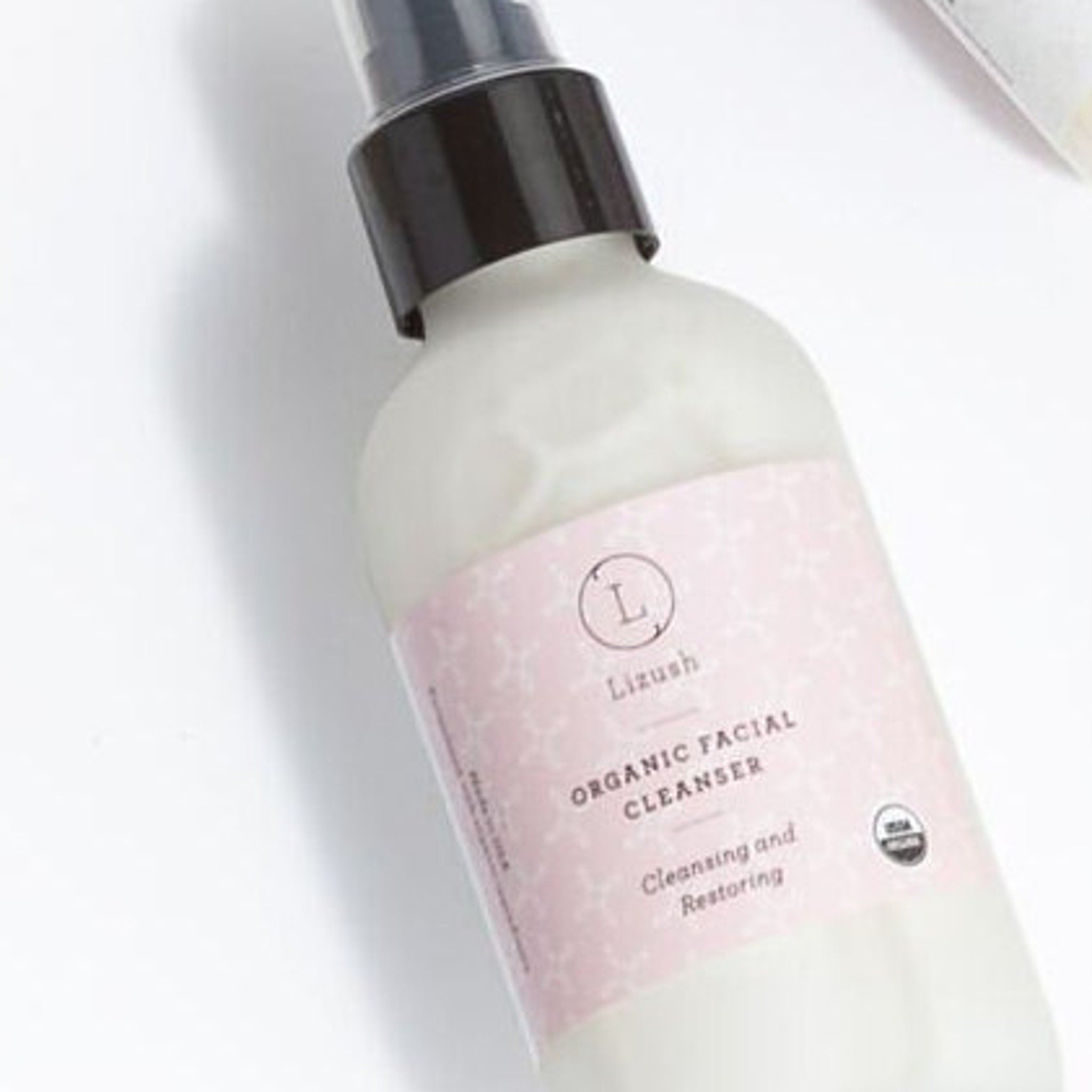 Facial cleanser bottle with black cap, pink label, and "Lizush" text visible