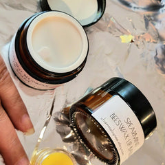 Lip balm jars, brown glass with black lid and white label, on foil surface