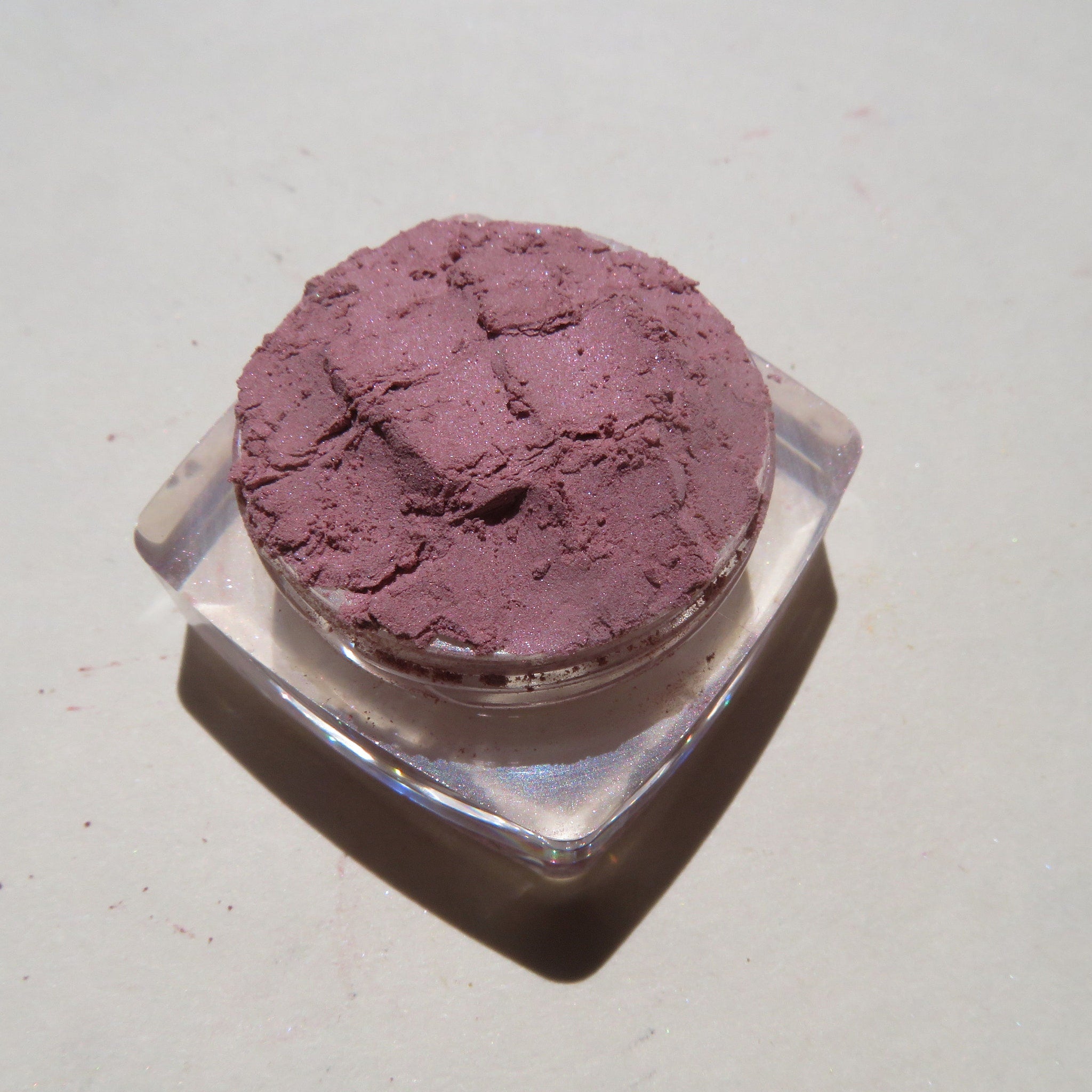 Hand applying pale mauve mineral eye shadow with a fluffy brush for soft, blended coverage