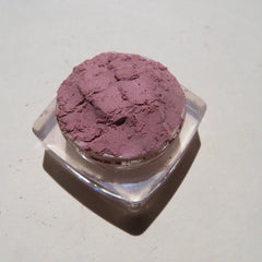 Hand applying pale mauve mineral eye shadow with a fluffy brush for soft, blended coverage