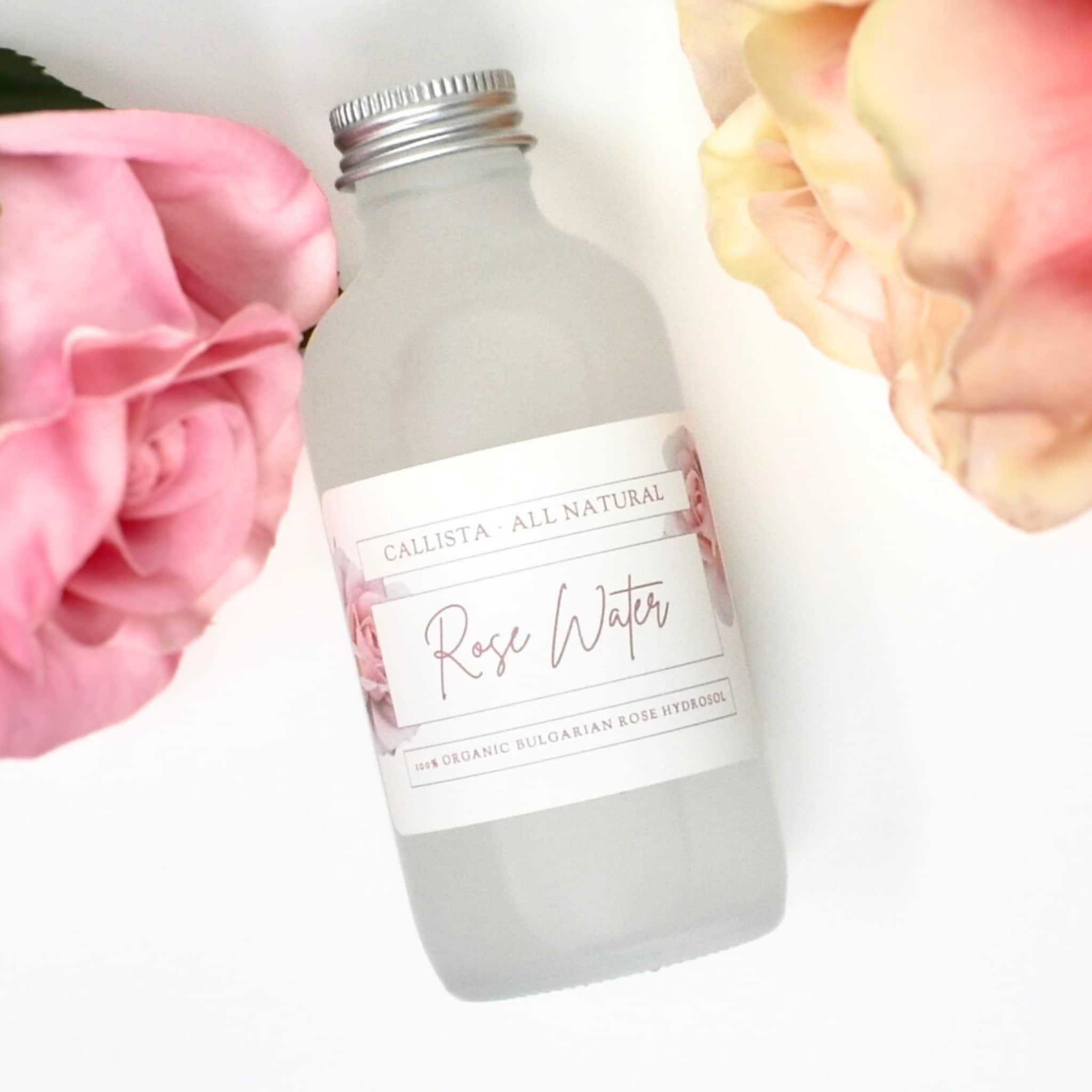 Rose water bottle, frosted glass, silver cap, Callista Naturals label, pink roses in background