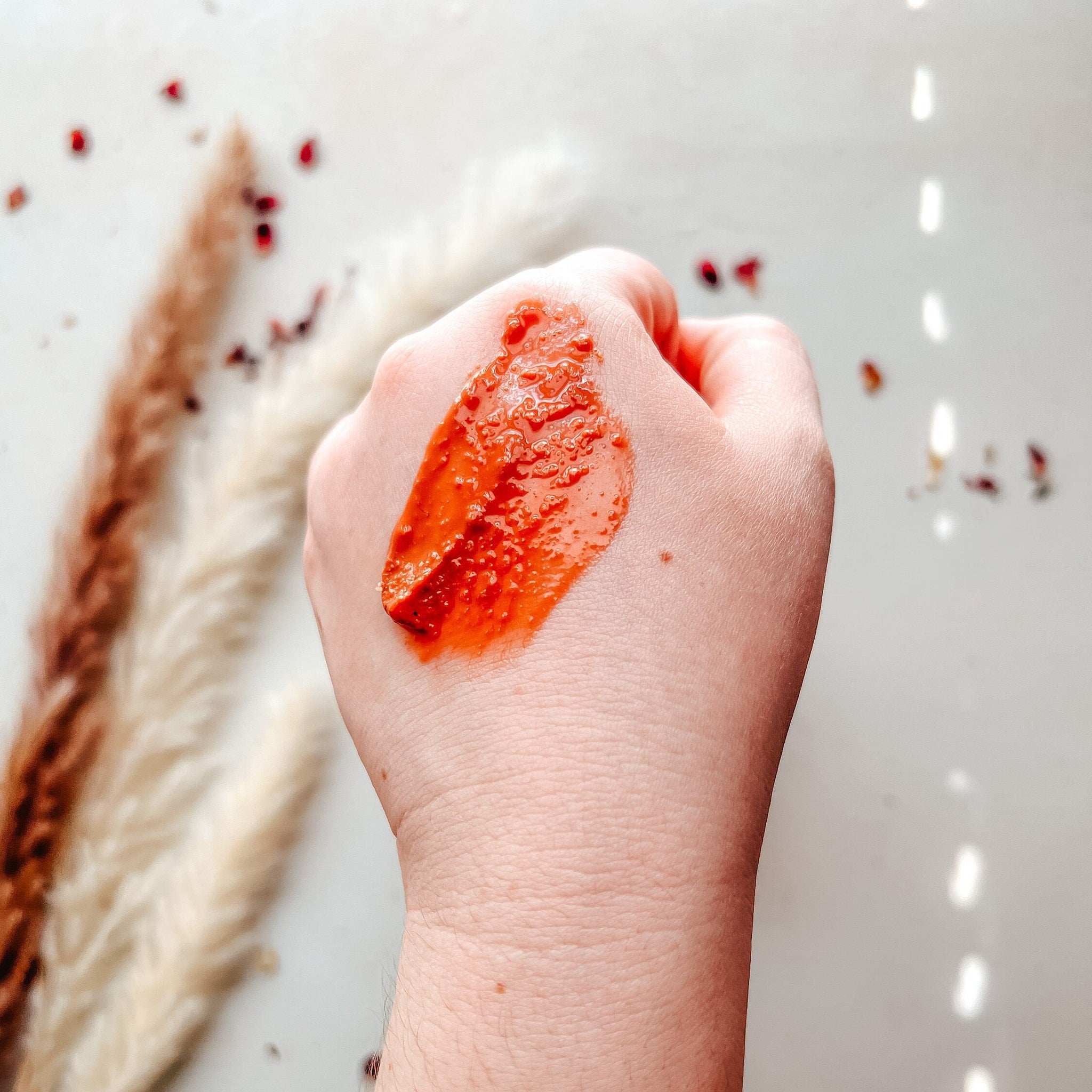 Red face mask on hand, textured orange color, applied on skin