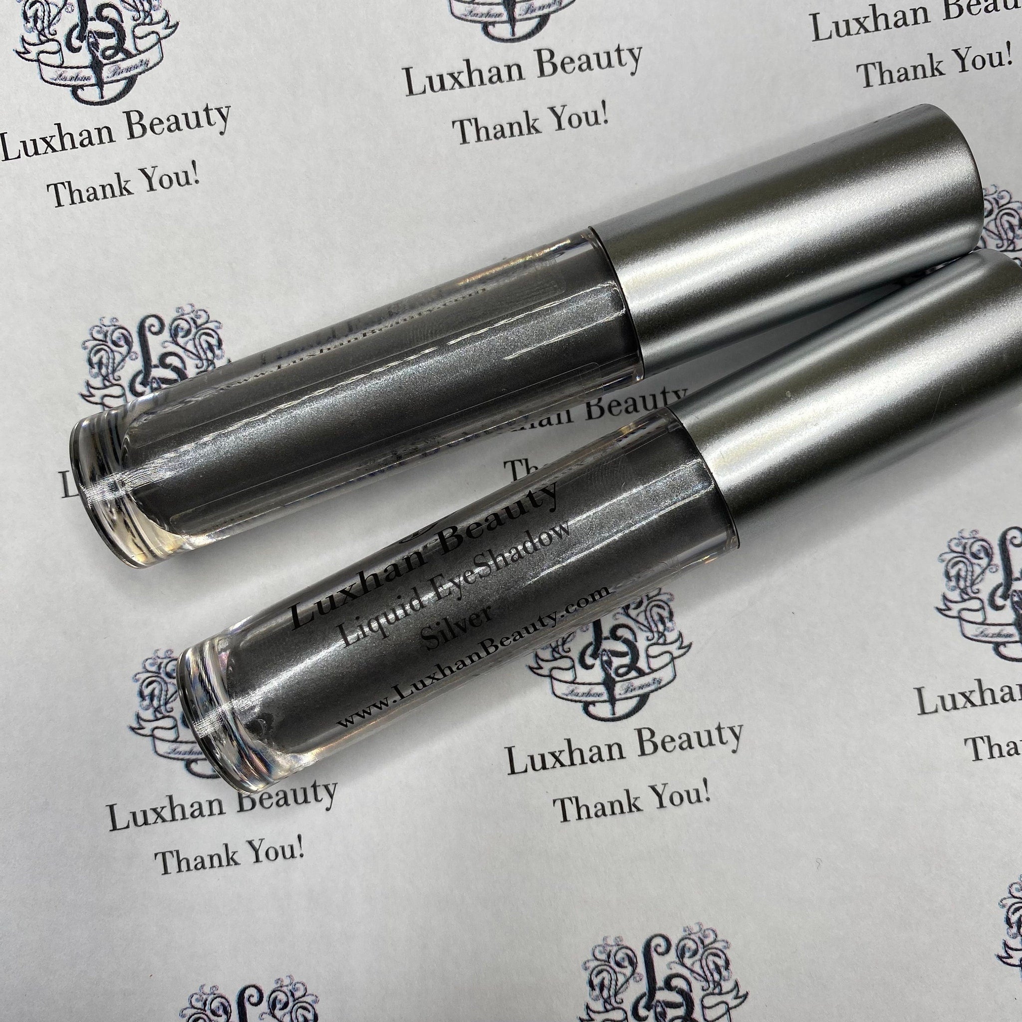 Hand applying shimmery silver liquid eyeshadow with glitter, creating a bold metallic statement on eyelid