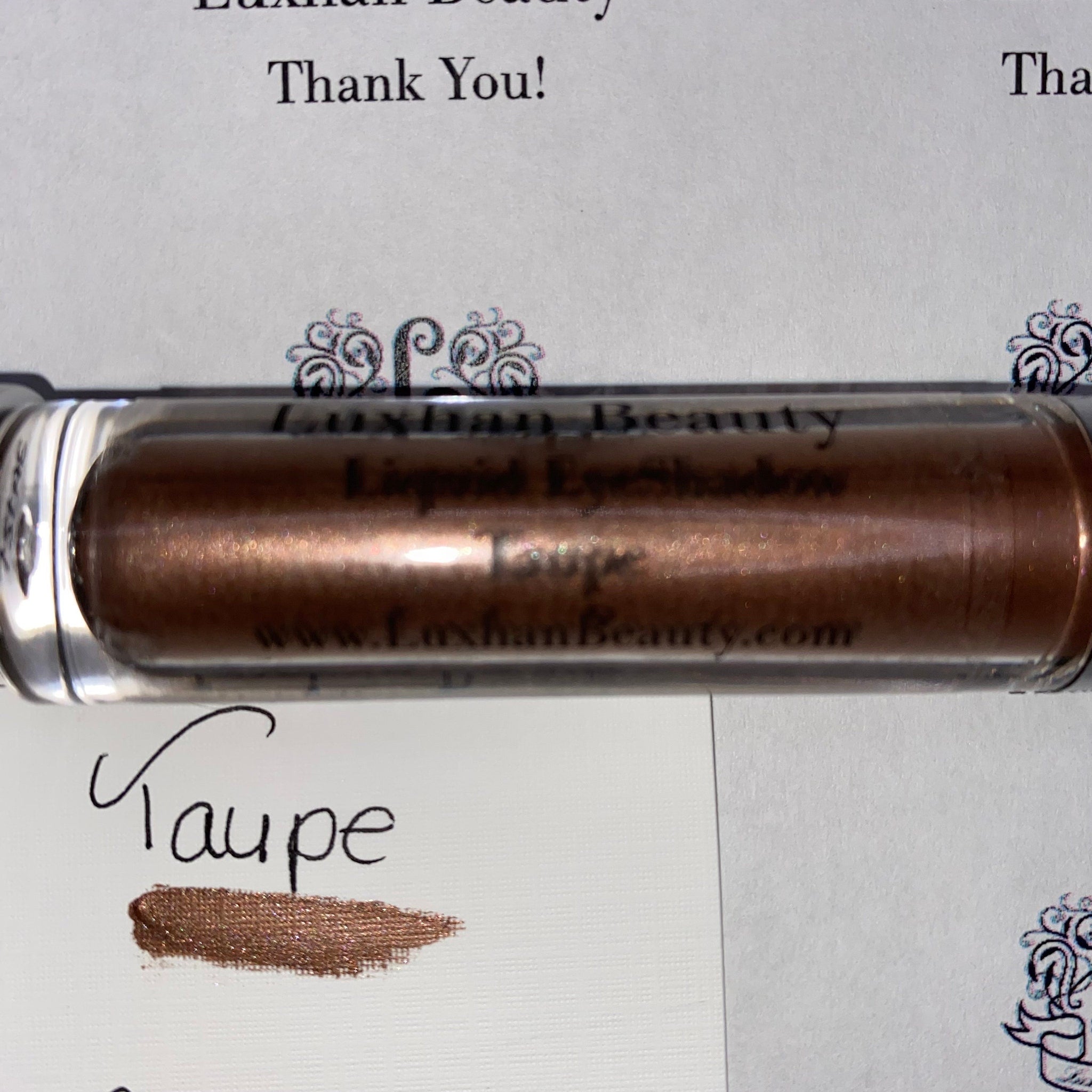 Liquid Eyeshadow metallic taupe shimmer in clear tube, Luxhan Beauty label visible