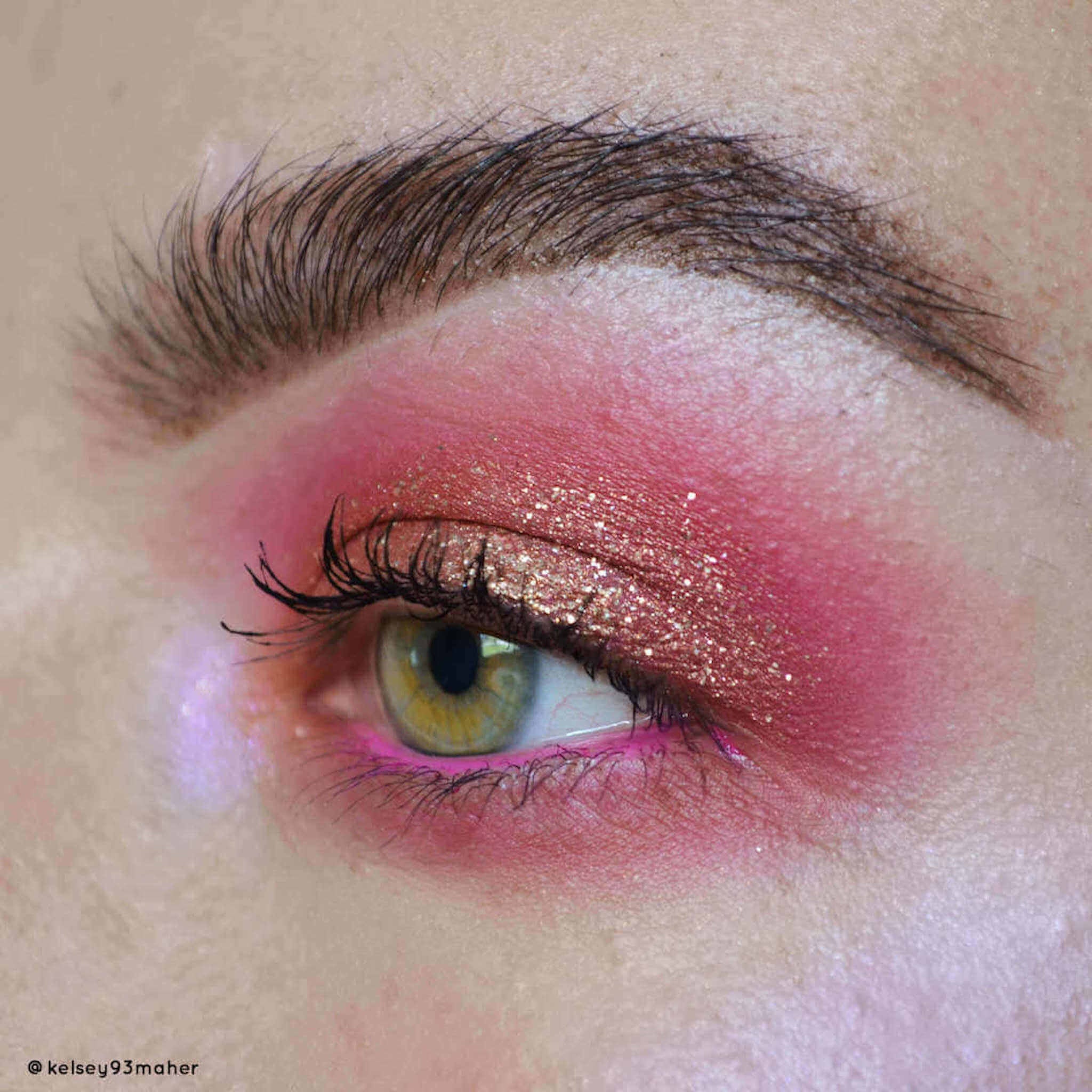 Eye makeup with pink and gold glitter eyeshadow, black eyelashes, and pink eyeliner on eye