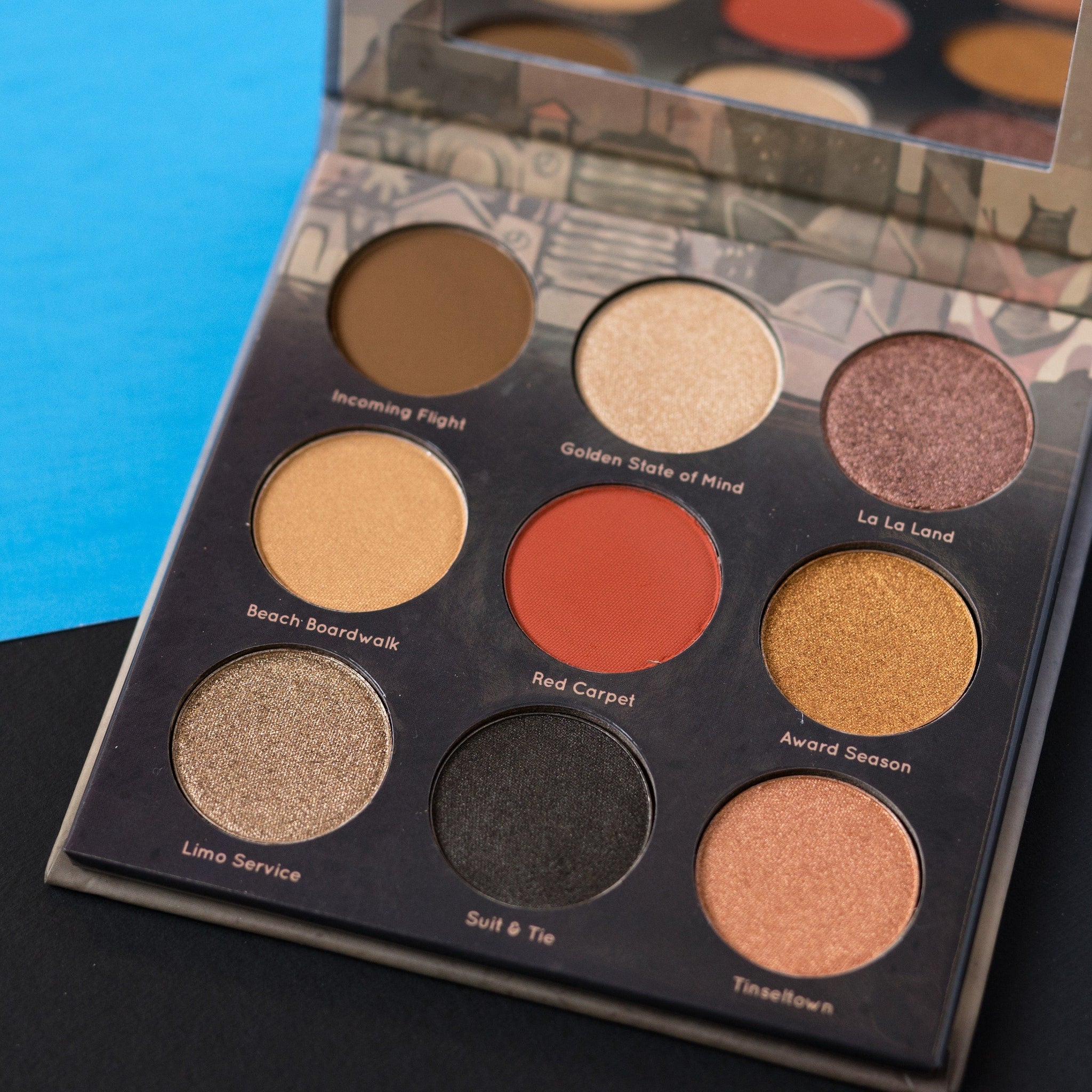 Eyeshadow palette with various shades of brown, gold, and red in a compact case with a mirror.